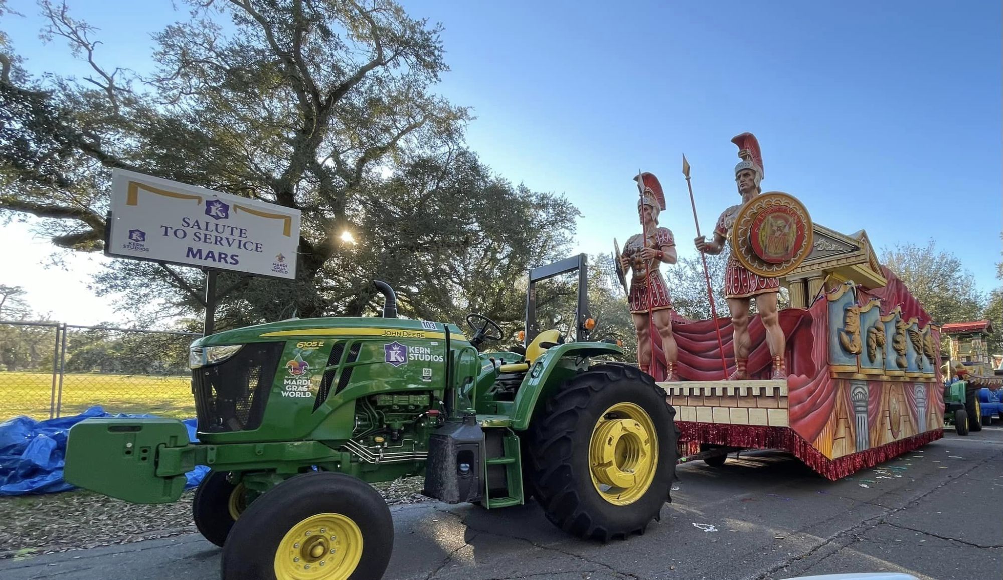 A green tractor carrying parade floats.