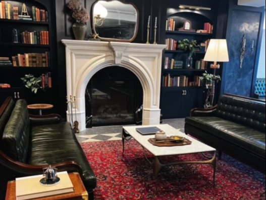 A living room with dark blue walls, green leather sofas, and a white fireplace