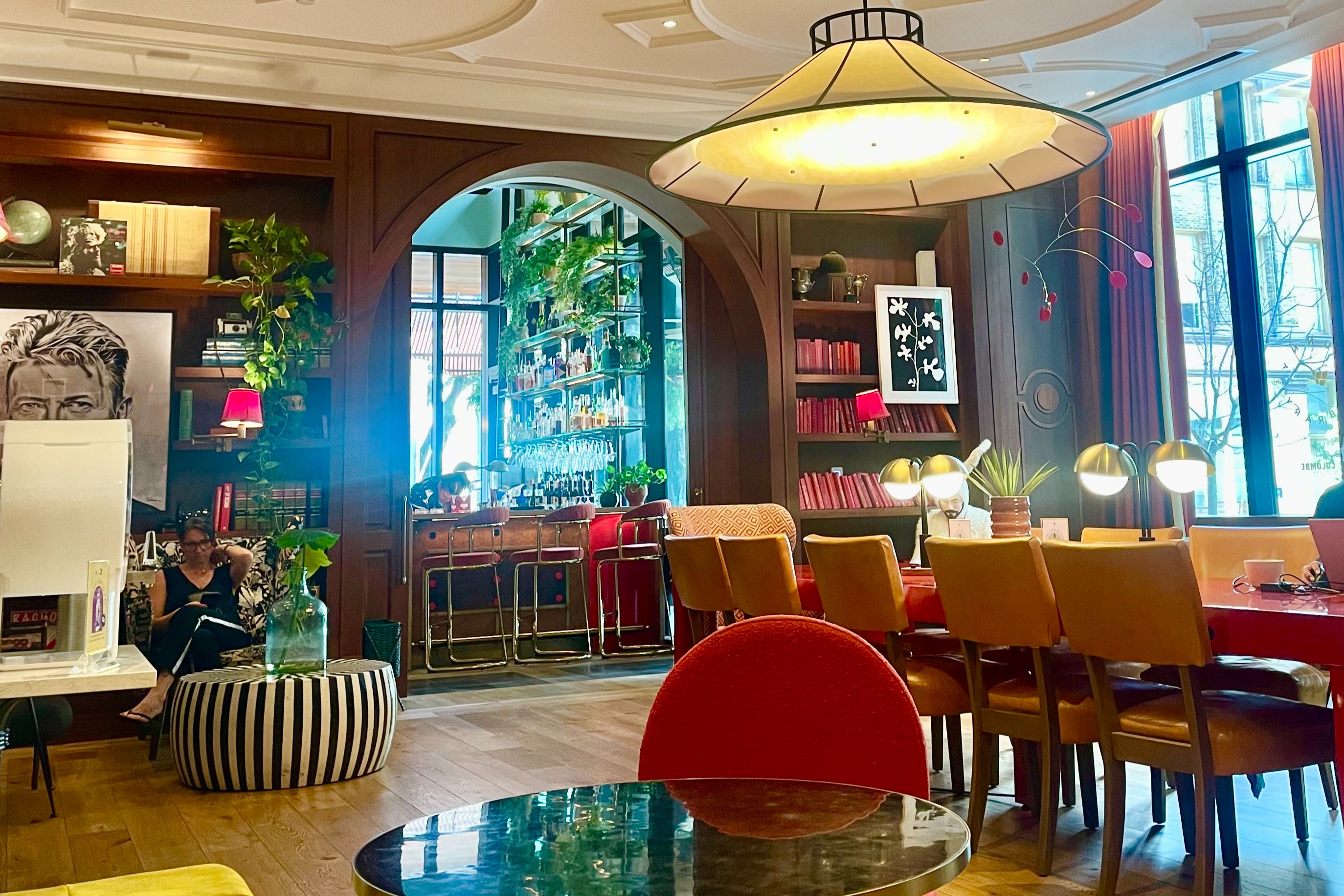 The cozy Funny Library Coffee Shop, with a long table and leather chairs, bookshelves and large windows.