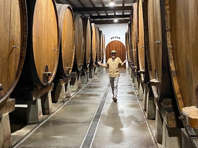 A man standing between wine barrels.