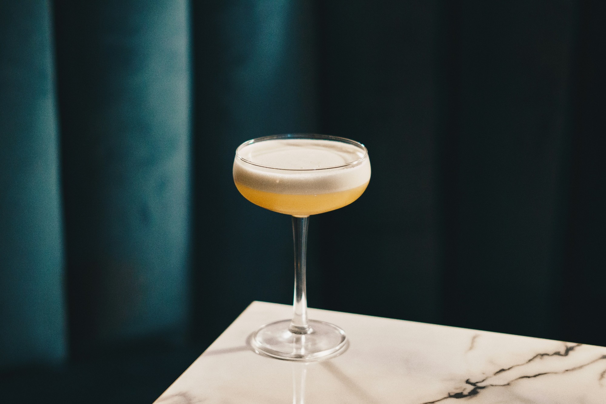 coupe glass with yellow foamy cocktail