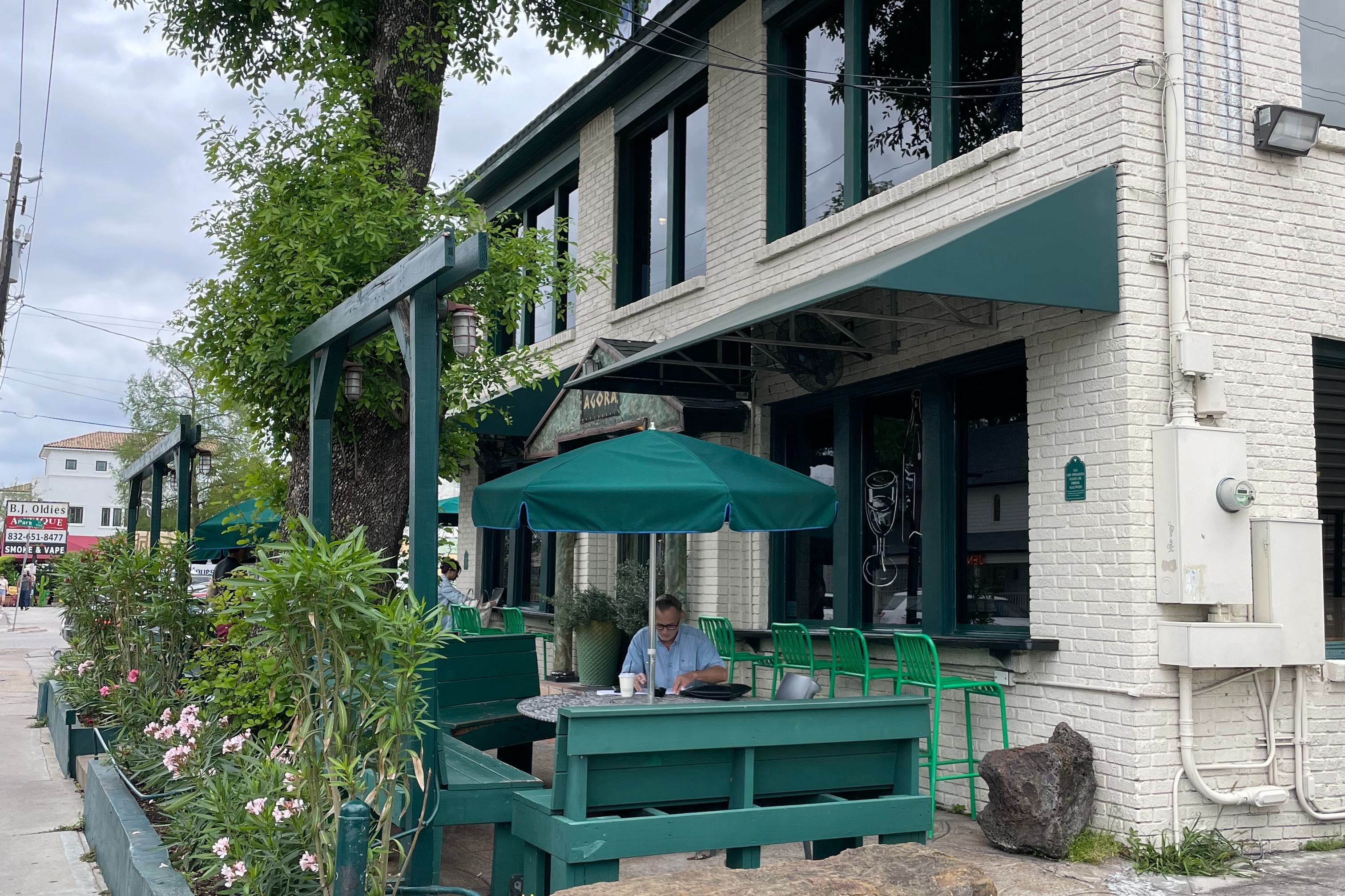 An outdoor seating area of a coffee shop with teal umbrellas and tables