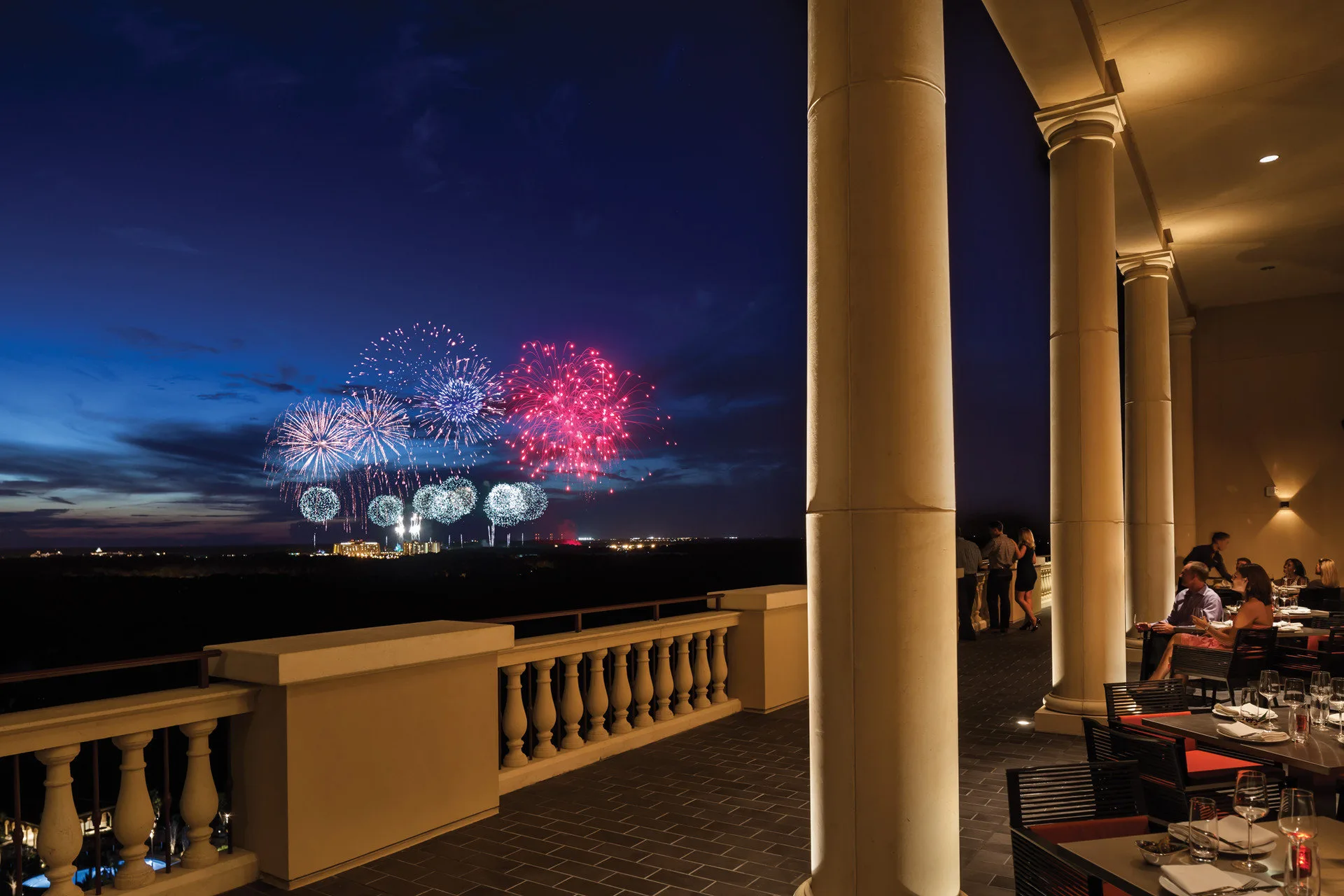 Fireworks blaze in this distance, visible from one of Four Seasons Resort Orlando's rooftop restaurant