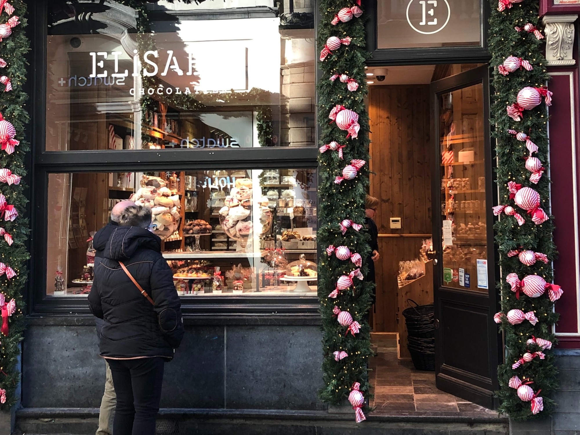 A woman standing in front of a chocolate shop.