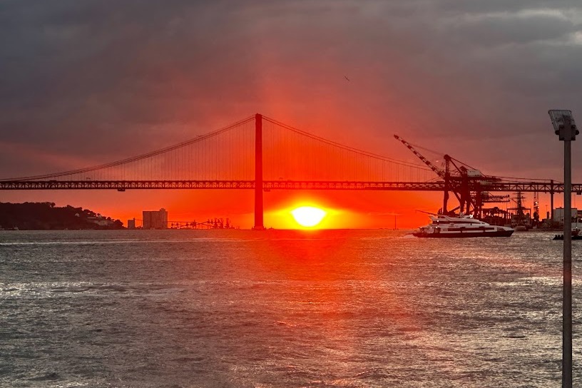 A beautiful orange sunset over the Tagus River and its impressive bridge