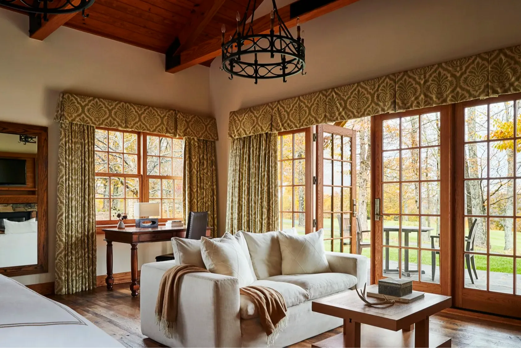 a handsome hotel room with a cozy white couch and lots of windows overlooking a green yard