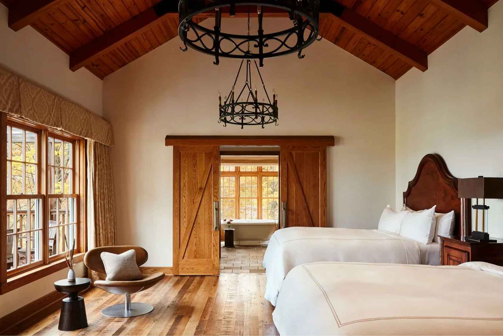 a bedroom in a stylish barn with a black iron chandelier