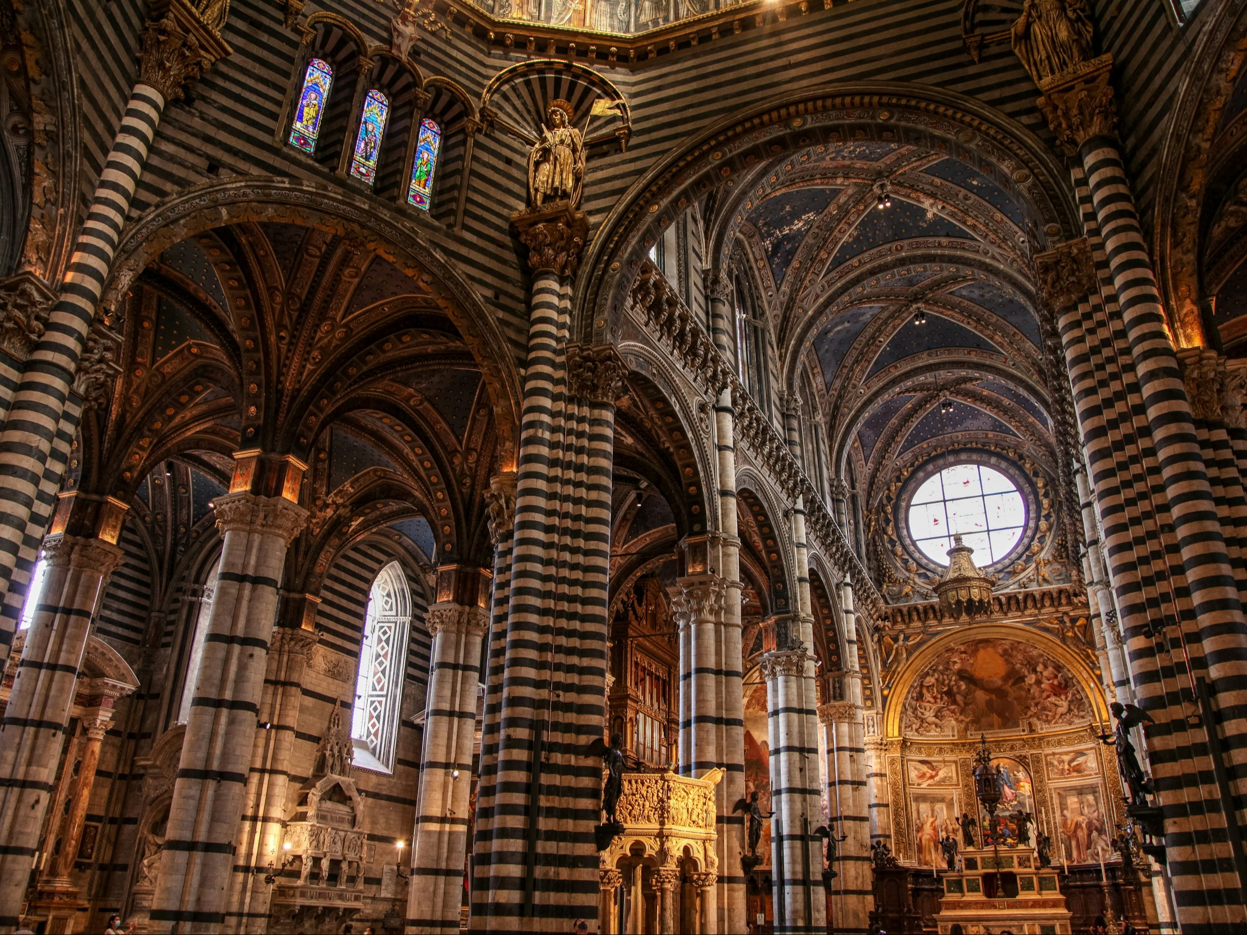 The image showcases the interior of a cathedral with striped vaults and stained glass windows, radiating grandeur and tranquility.