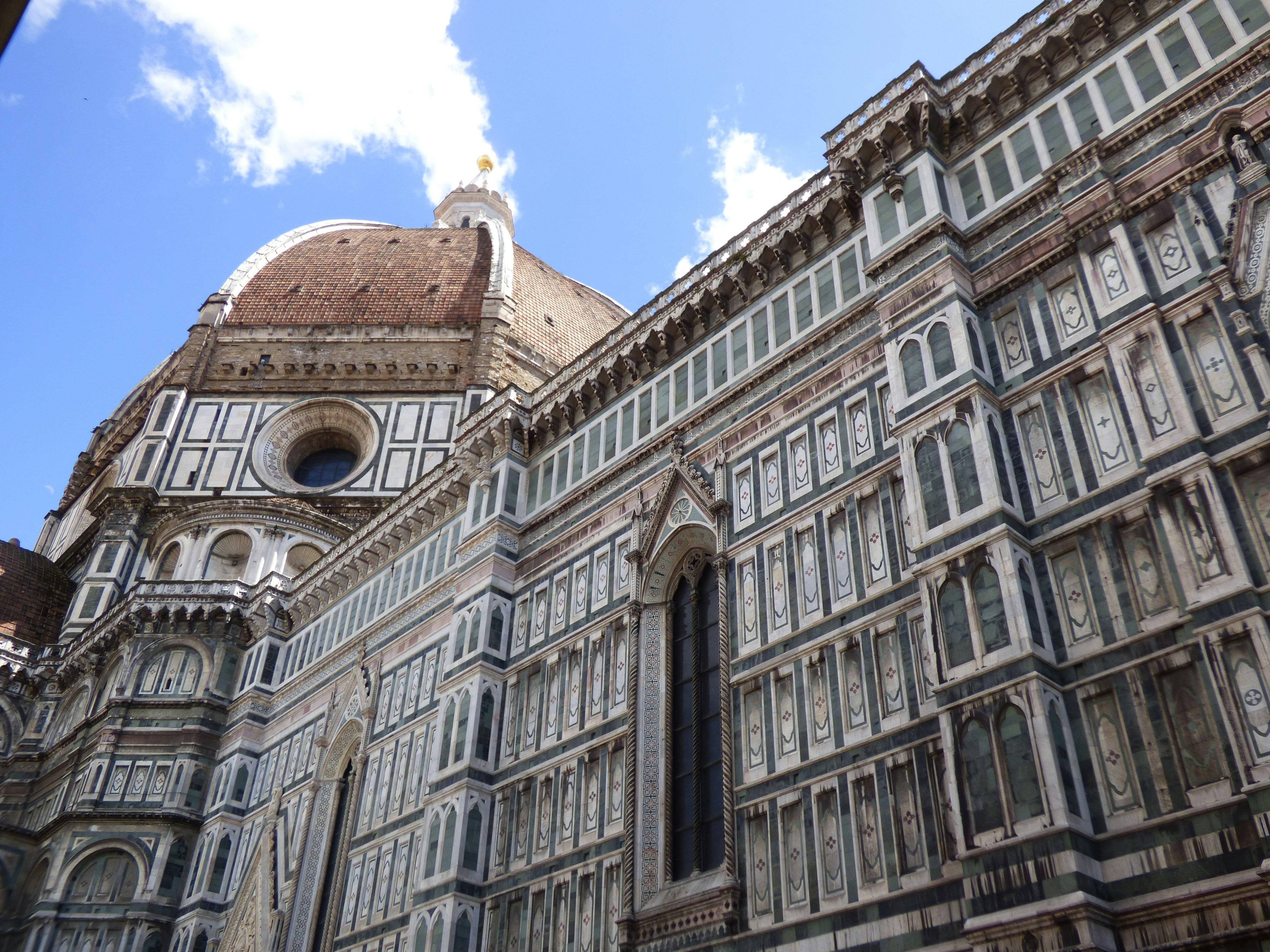 The image depicts the grand exterior of a cathedral with intricate marble patterns and a large dome, set against a clear sky.