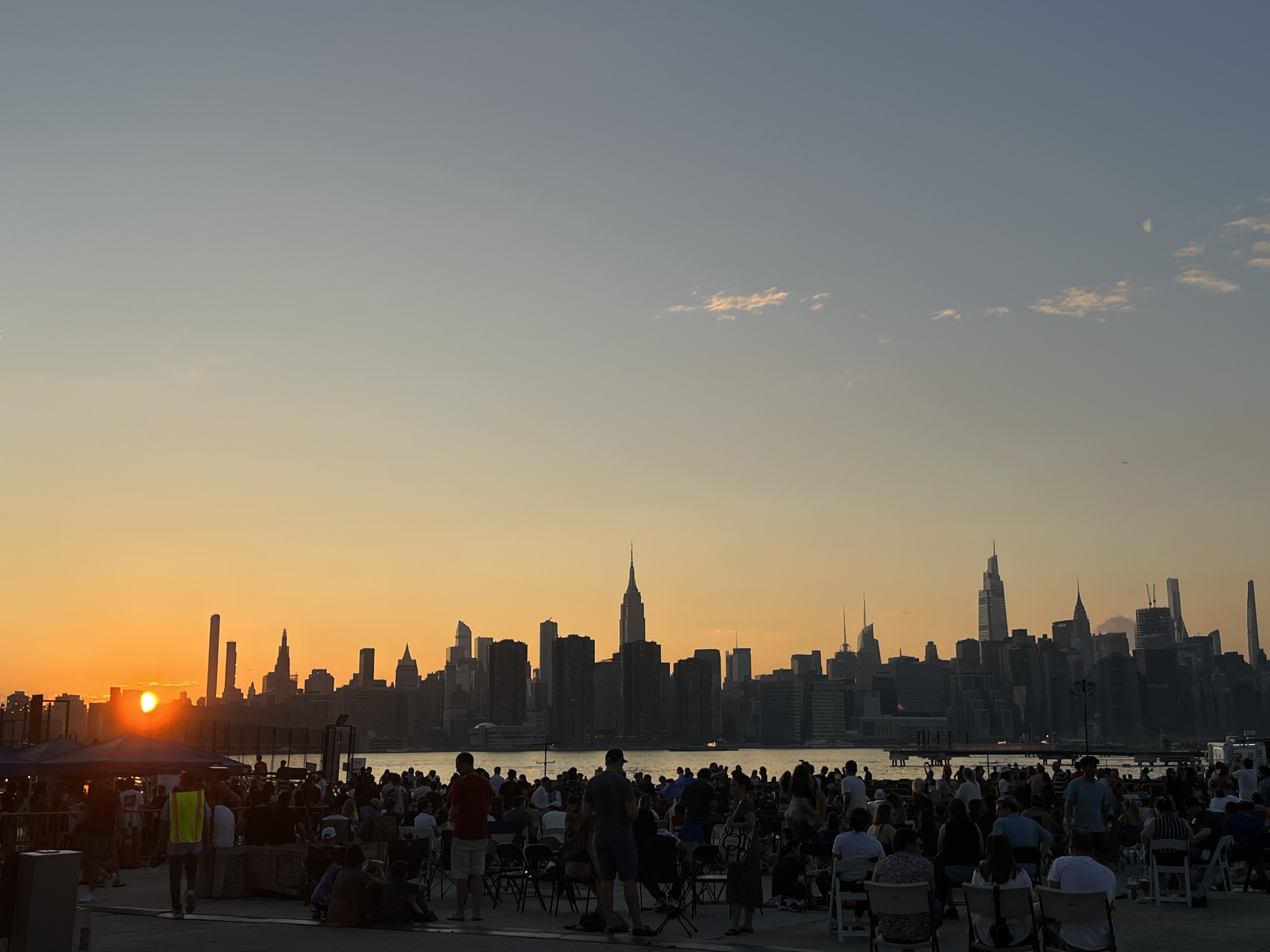 The view of Manhattan from skyline drive in, with people sitting outside at sunset.