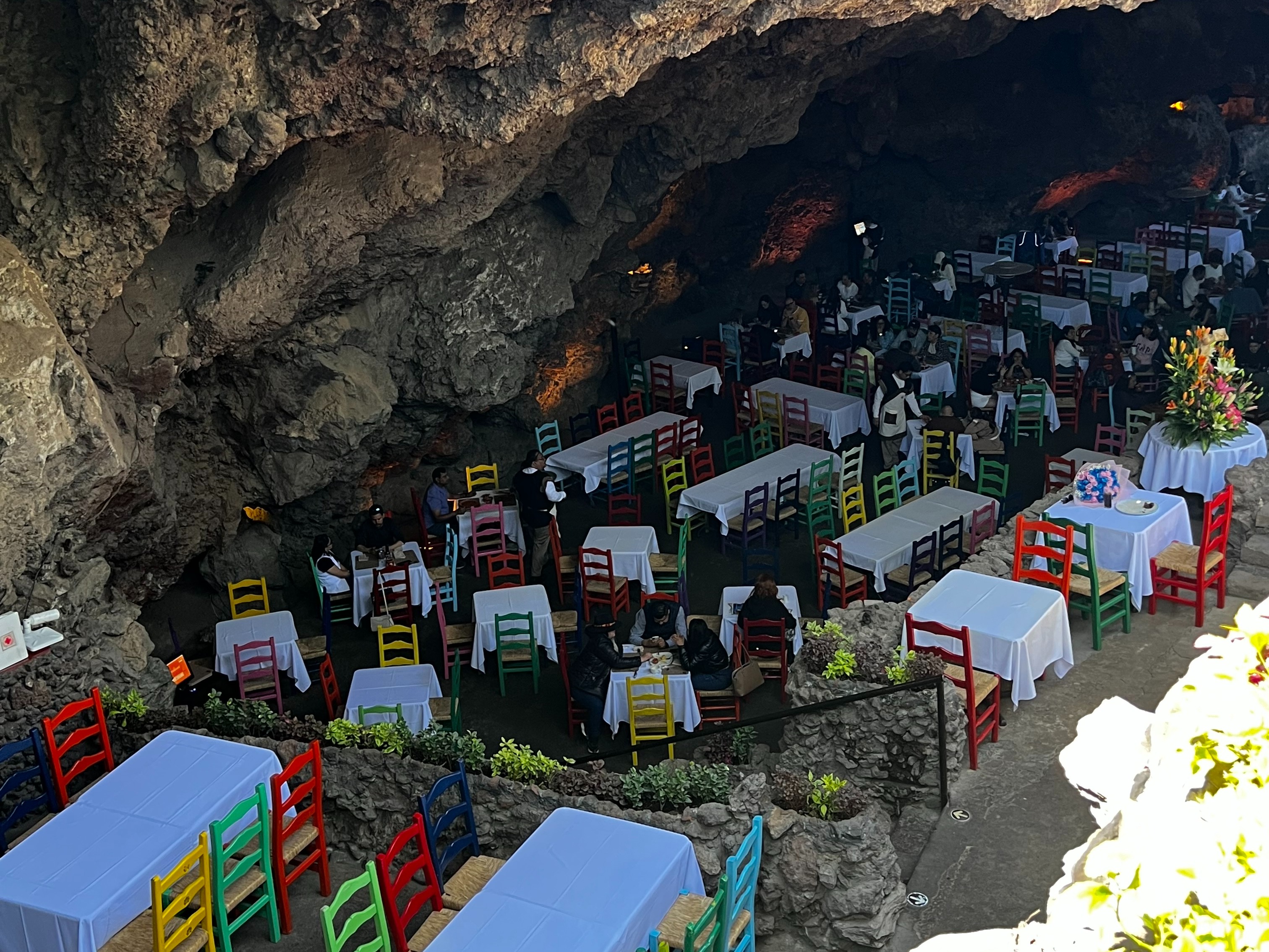 A beautiful view of colorful chairs and white tables inside of a cave.