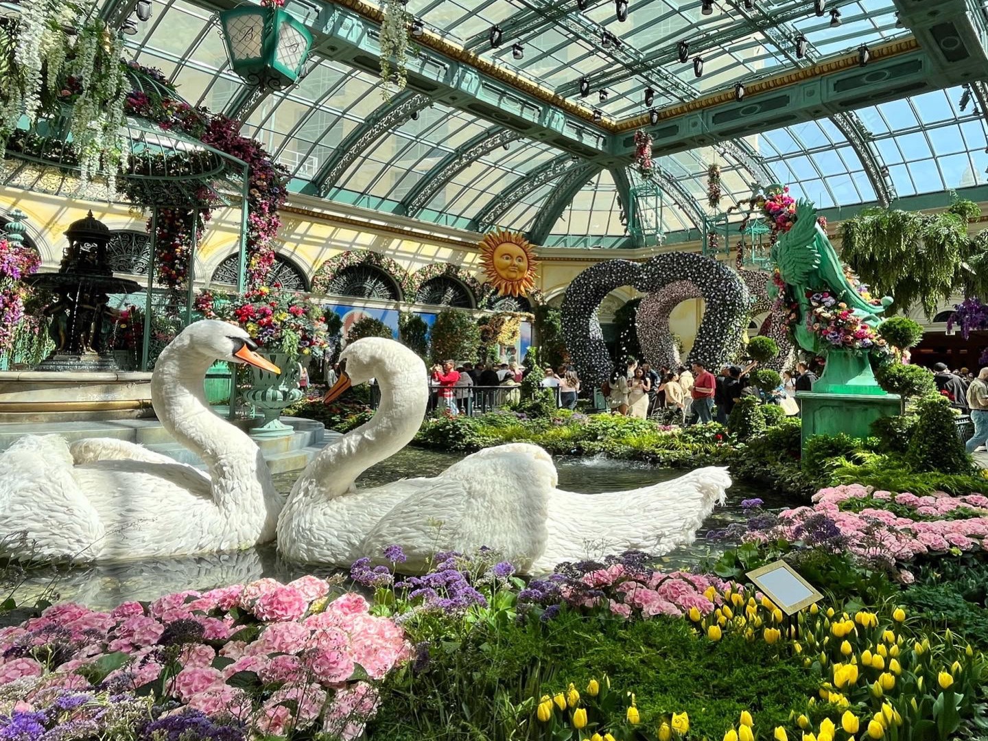 The image features an indoor garden with ornate decorations and swan sculptures, exuding a serene and artistic ambiance.