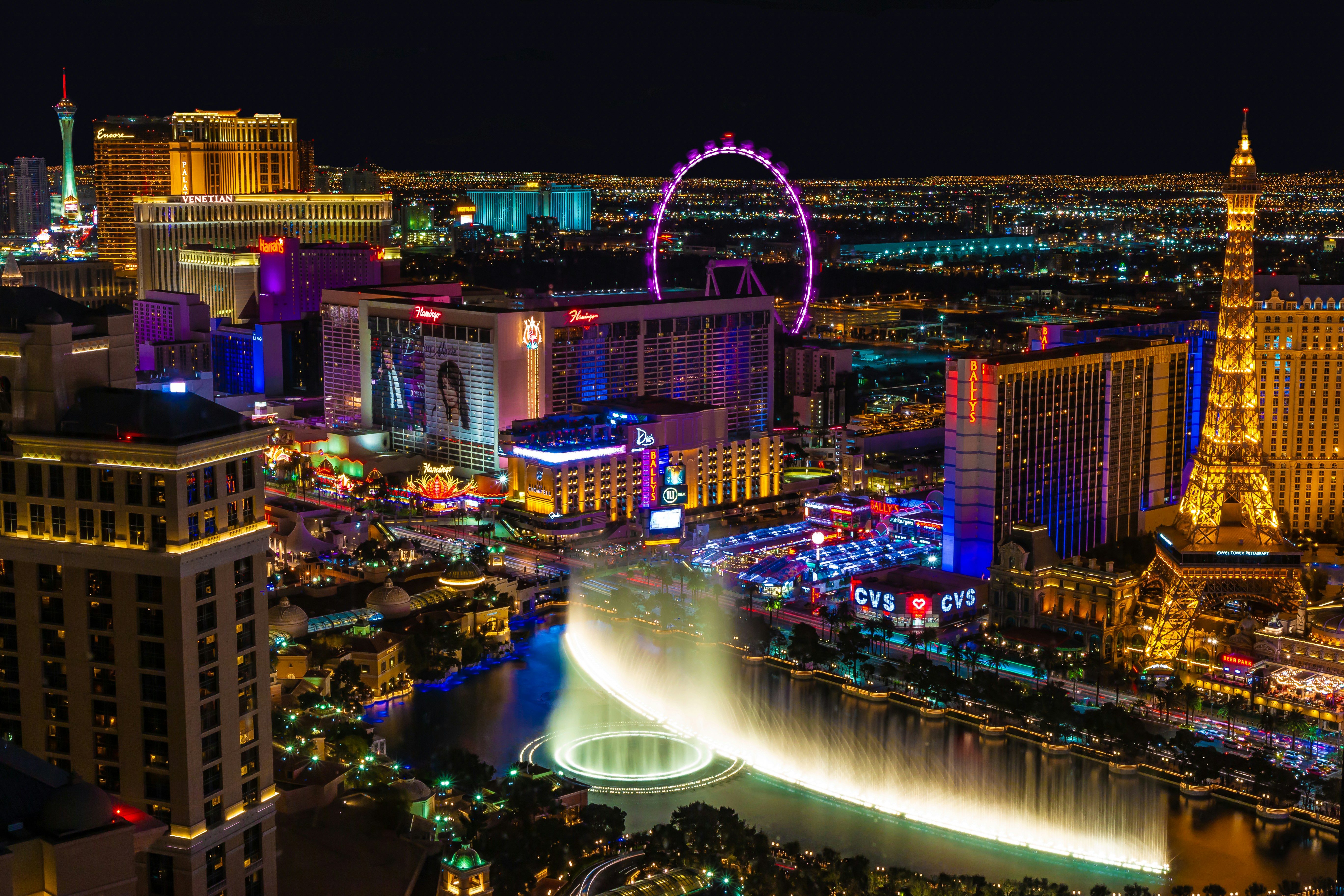The lit-up Las Vegas skyline at night, with views of the Eiffel Tower and ferris wheel.