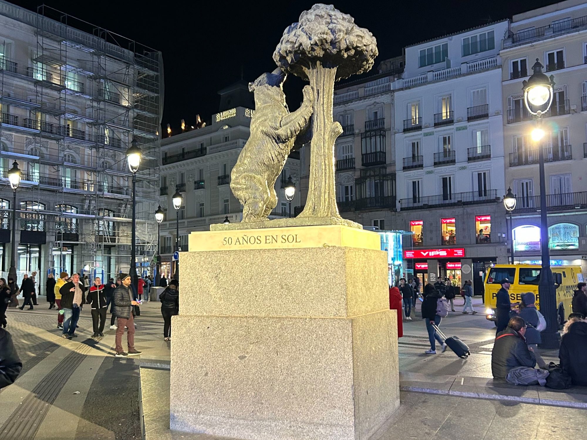 A statue of bear and tree in the middle of buildings.