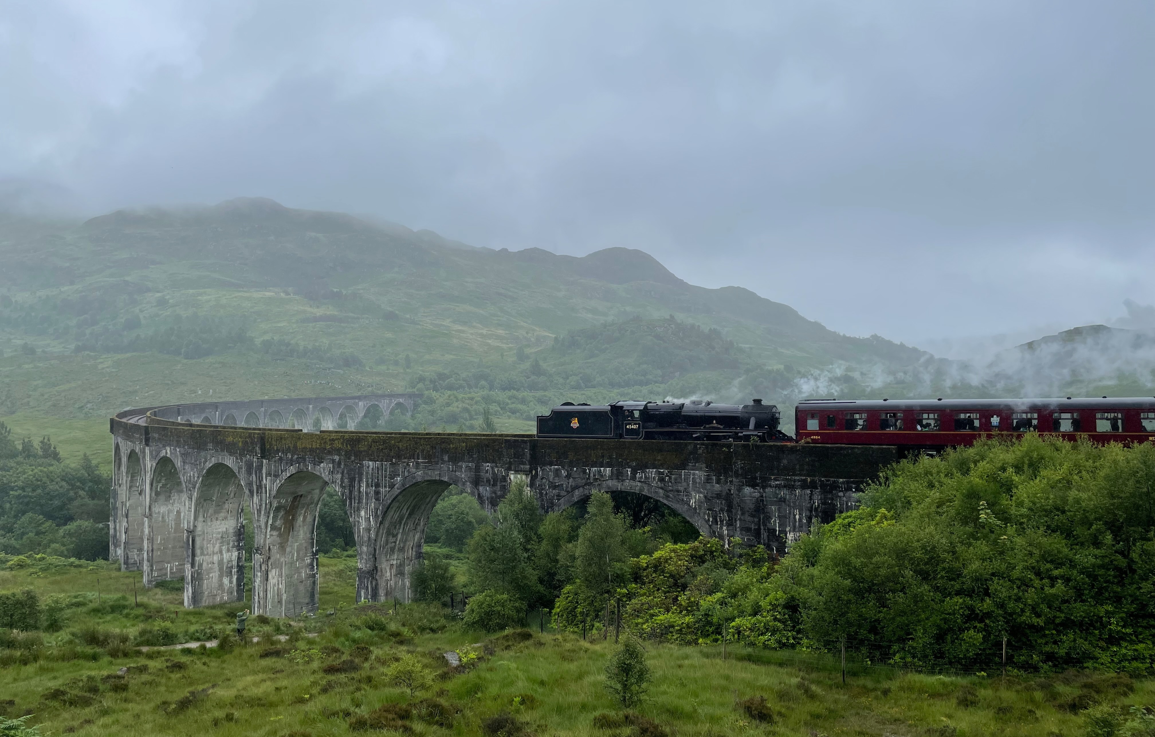 An aerial view of the ancient train track on a bridge near the green mountains.