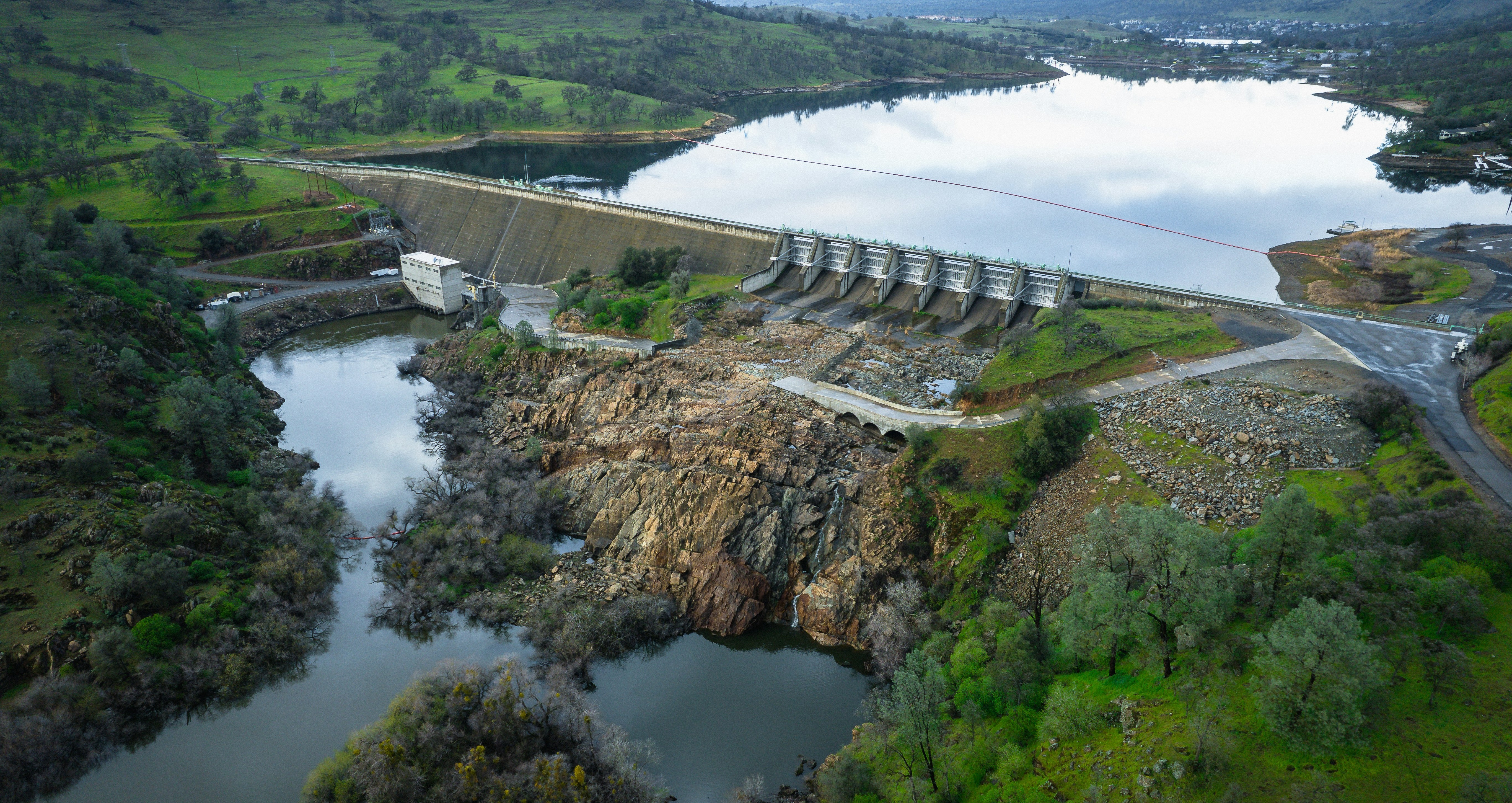 A serene dam amidst lush greenery, with a river flowing through, highlighting the harmony of nature and human engineering.