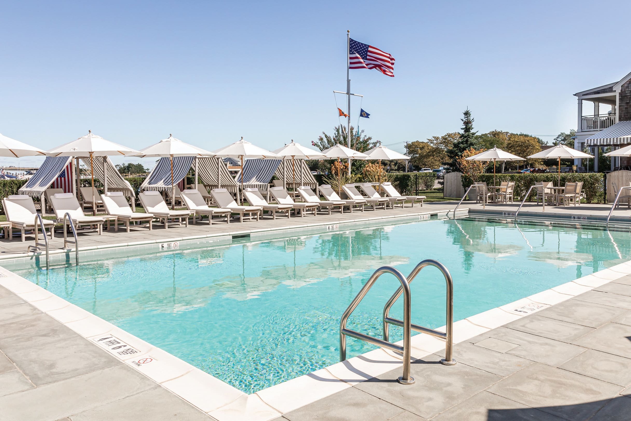 an outdoor pool surrounded by white lounge chairs and umbrellas