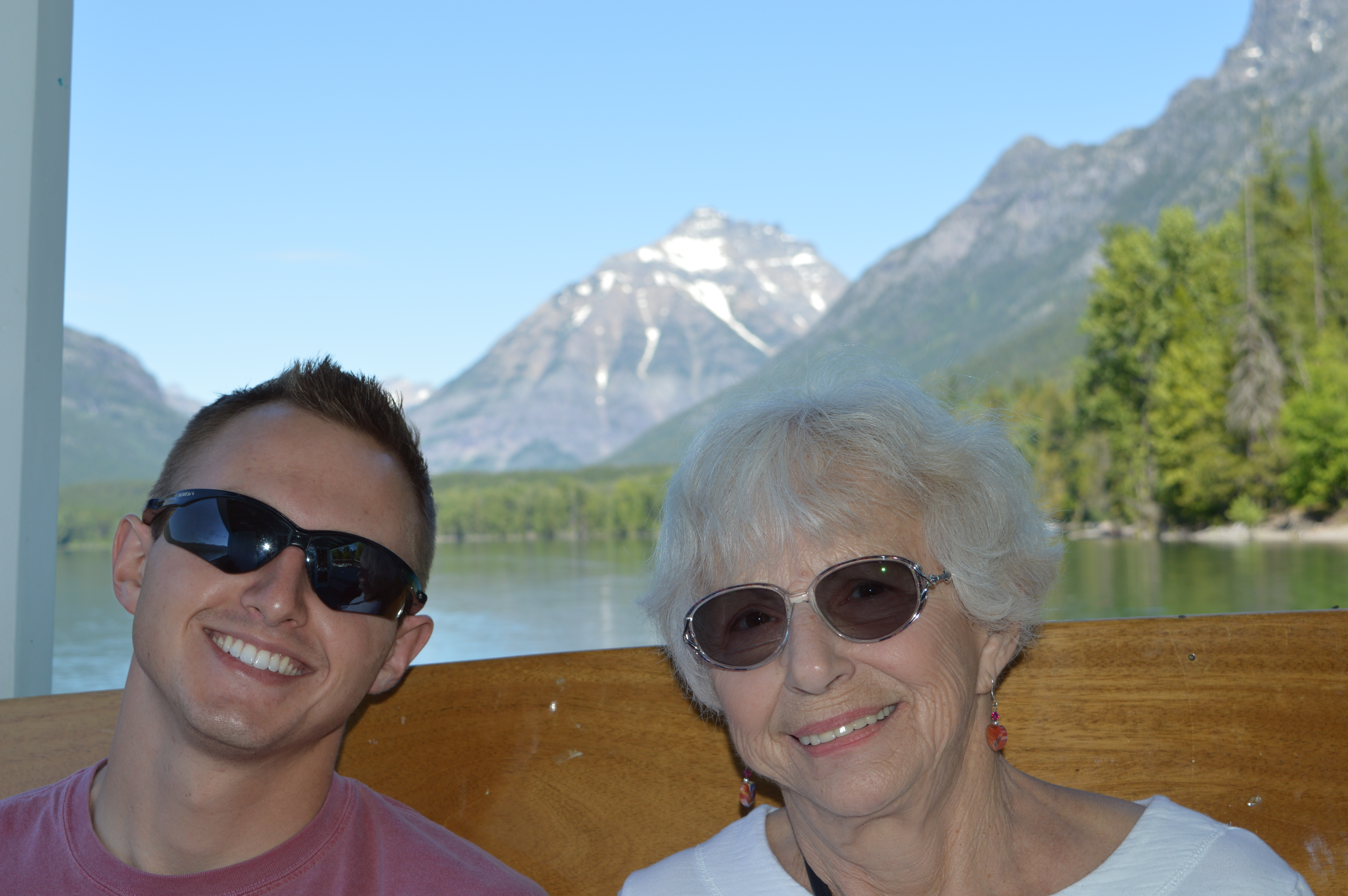 Two people posing for a photo with a body of water and mountains behind them
