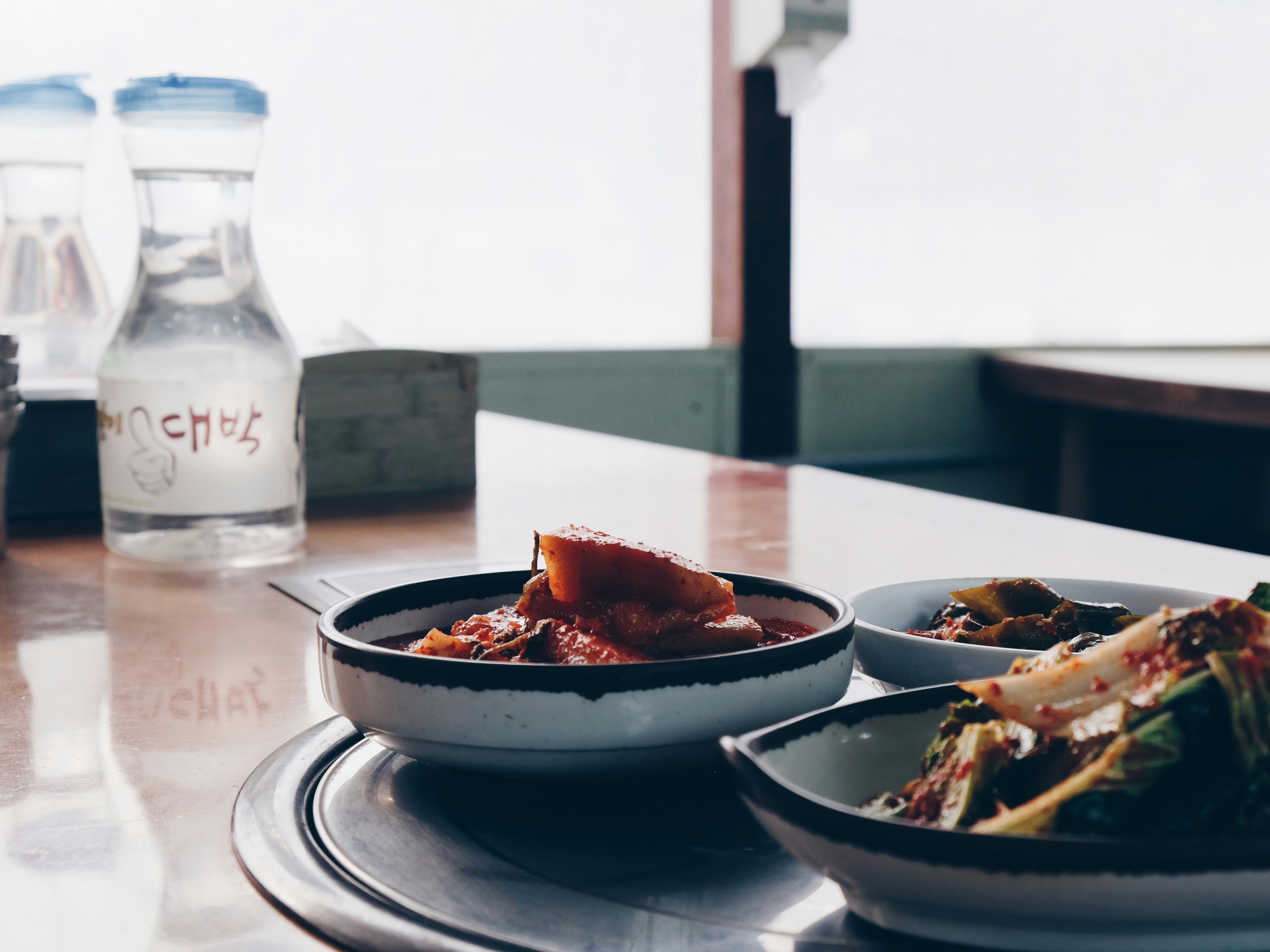 A picture of Korean cuisine served on a table with water in the background.