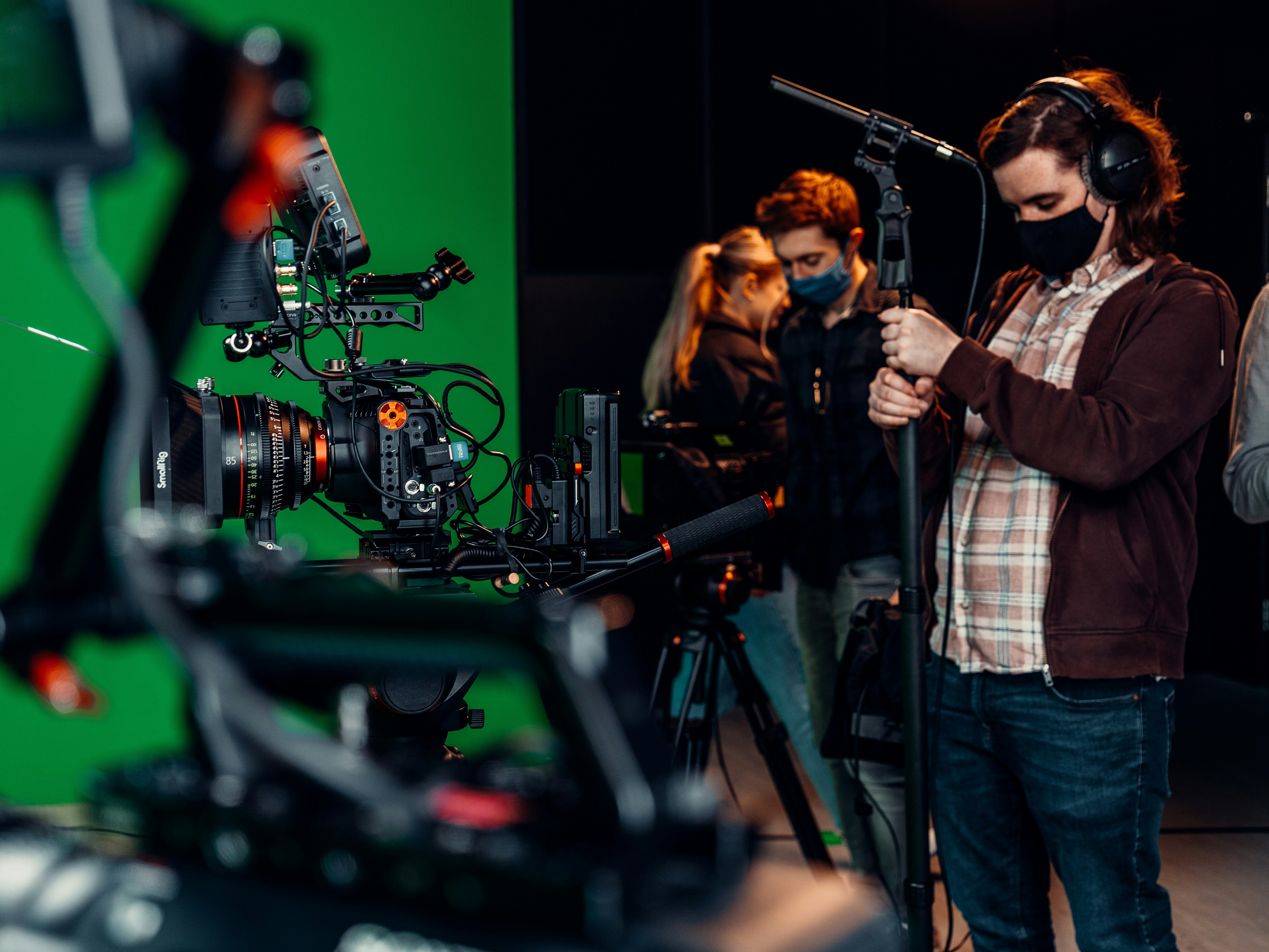 A picture of a group of people standing around a camera in a studio.