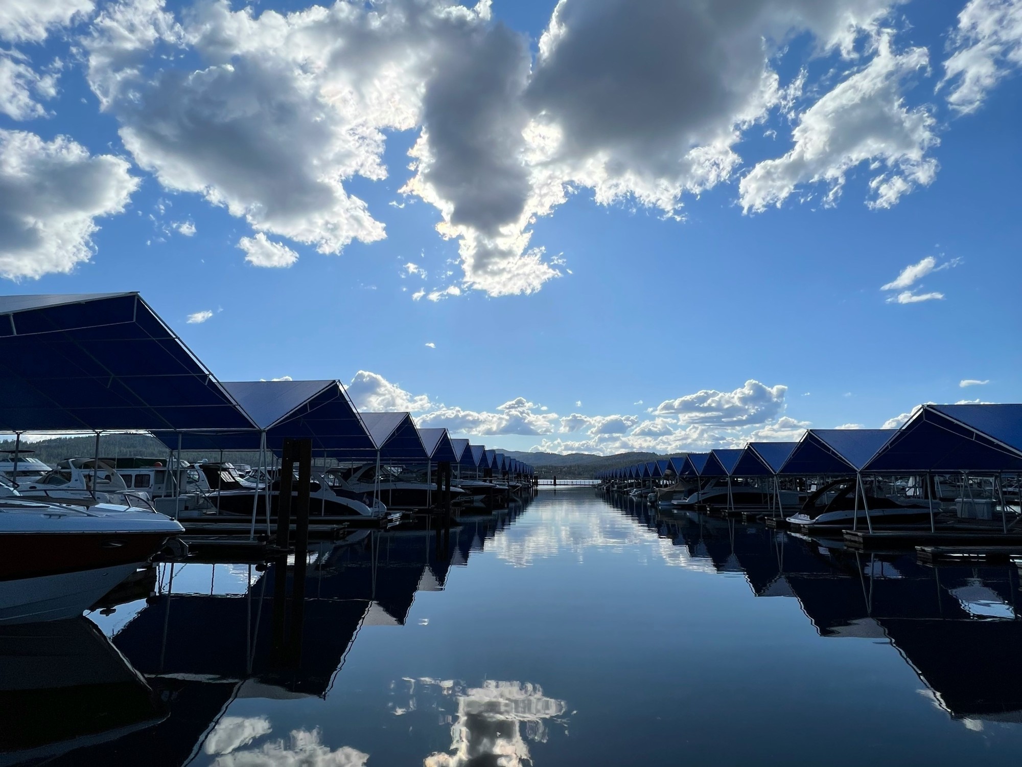 Body of water with boats and clouds reflection.
