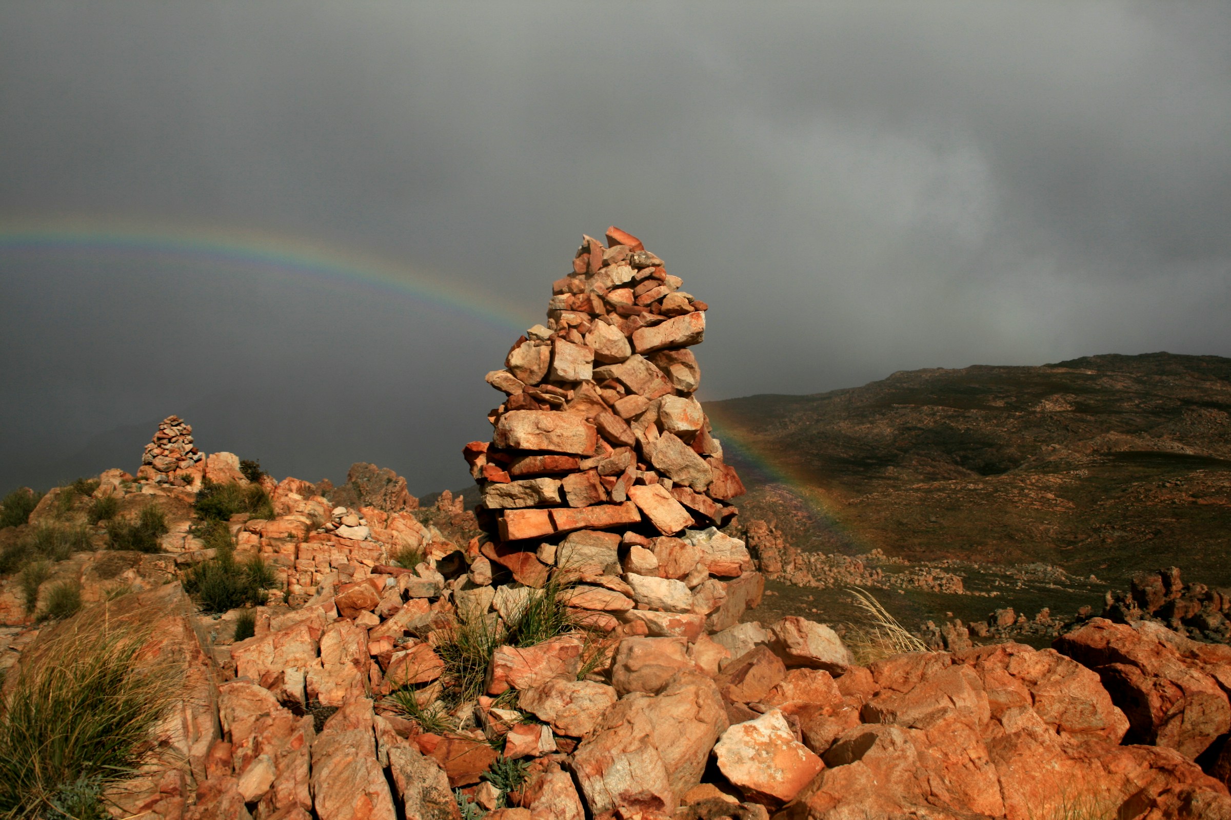 Pile of rocks on top of mountain with a rainbow in Cederberg, Western Cape.