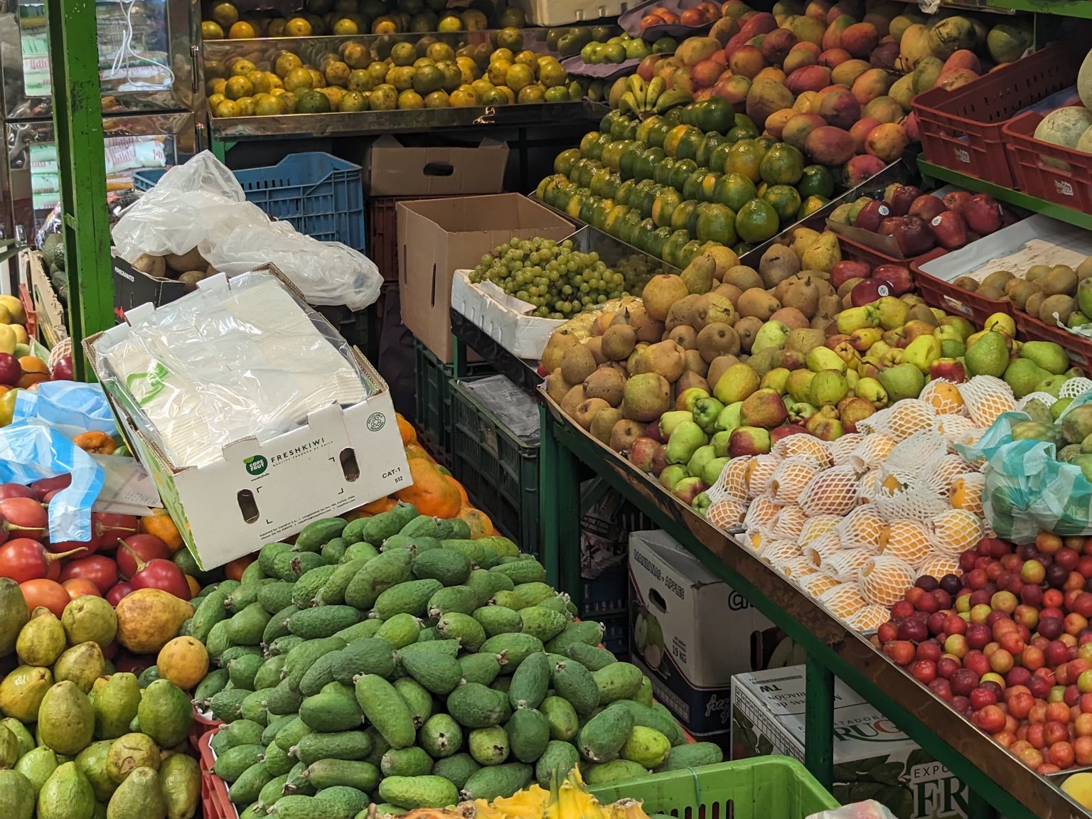 A fruit stall with various items on display and a white box holding a bundle of plastic.