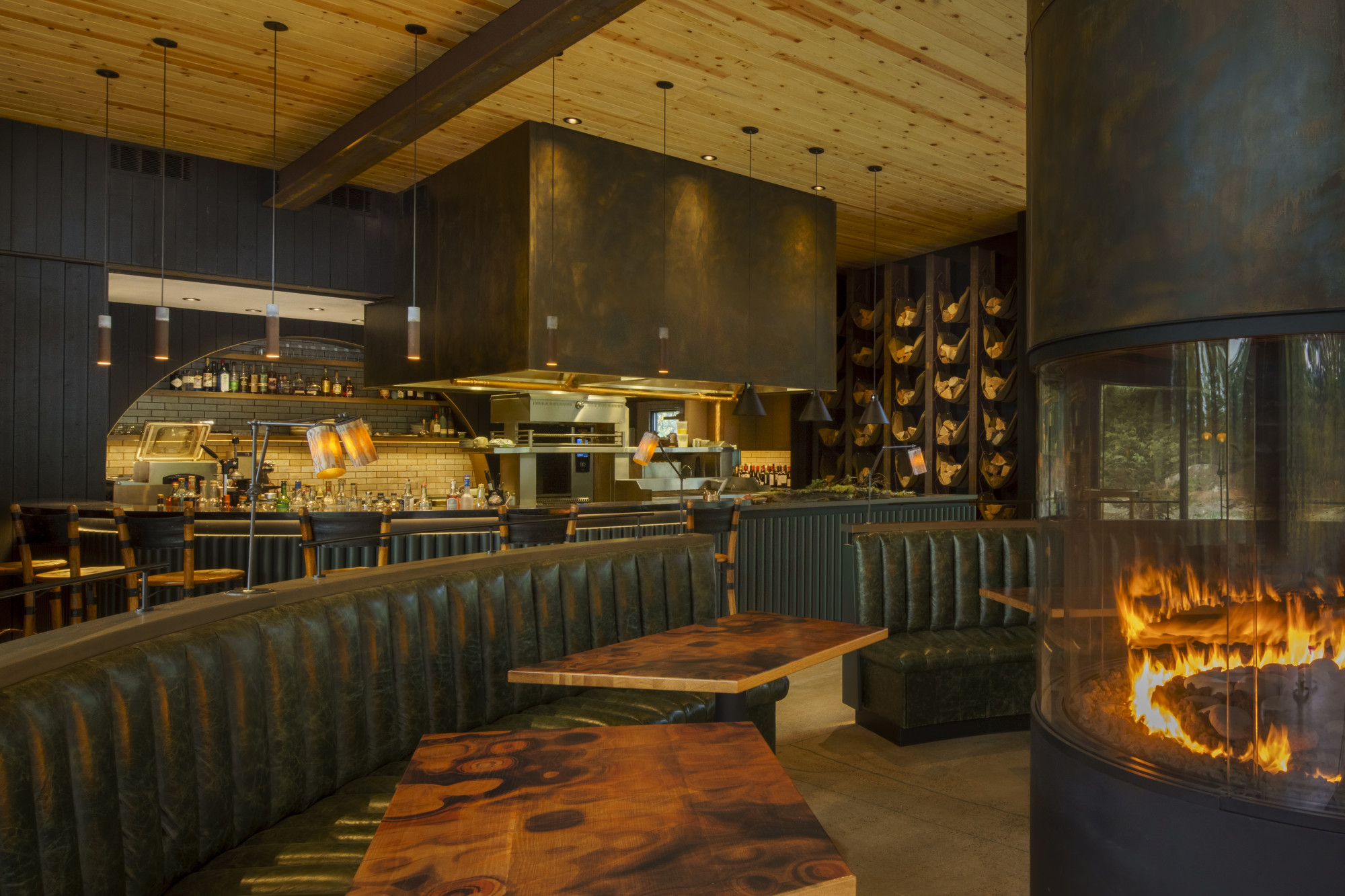 a sleek dining room with a central cylindrical fire place
