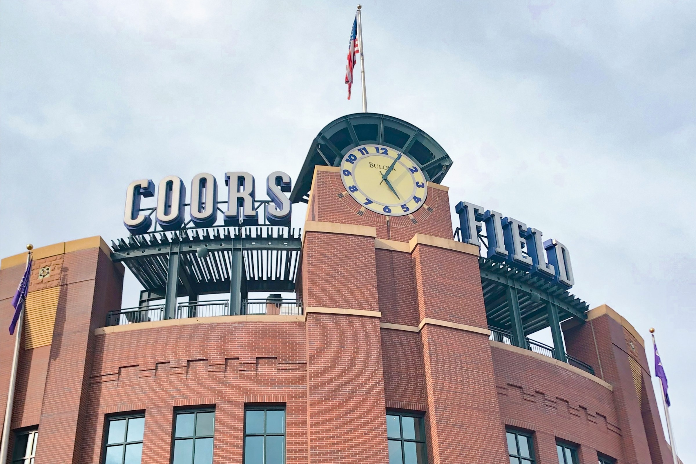 A picture of a brown concrete building with signage that reads Coors Field.