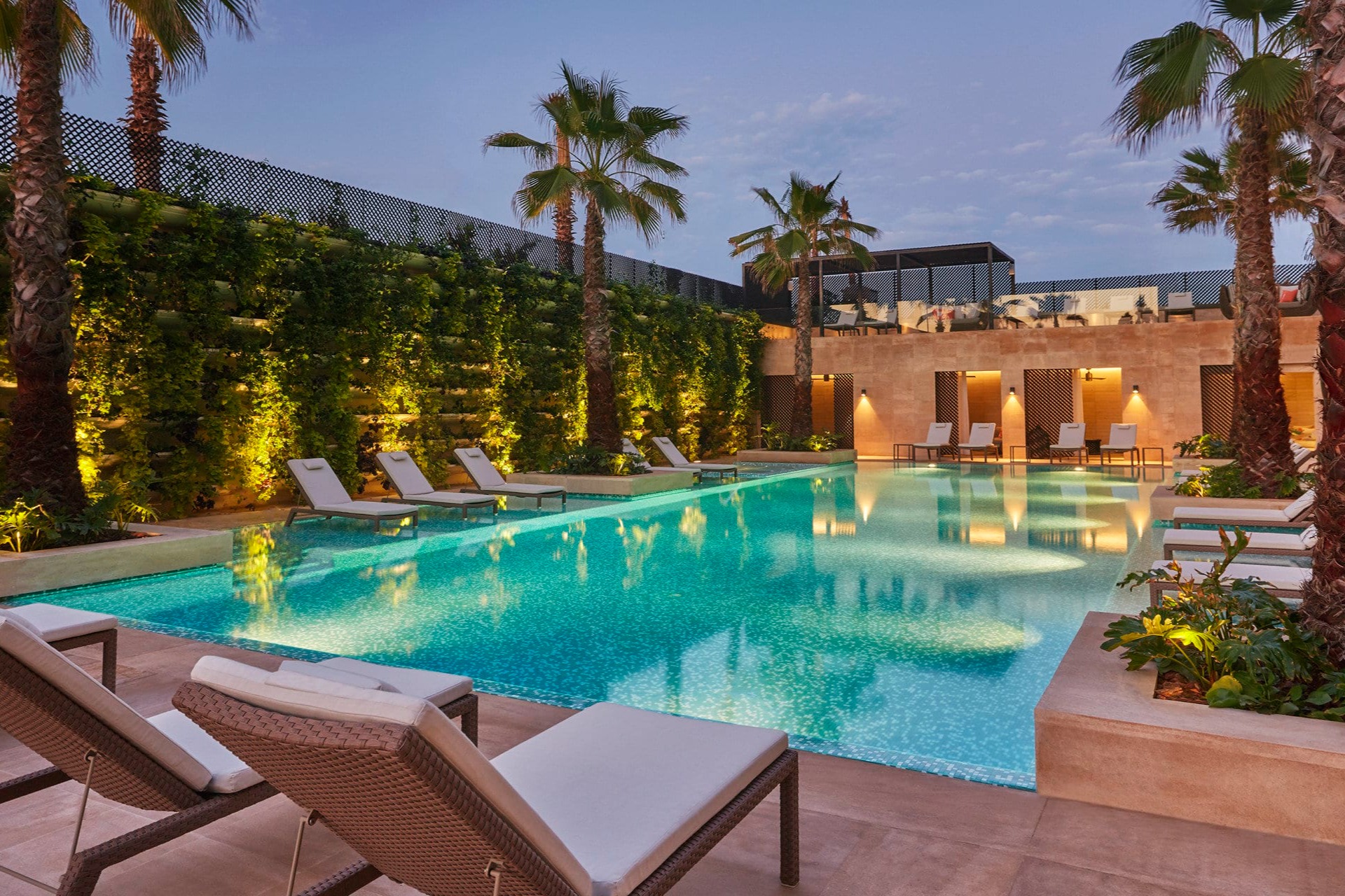 At dusk: vine-covered walls, palm trees and loungers surround a well-lit pool at Four Seasons Hotel Casablanca