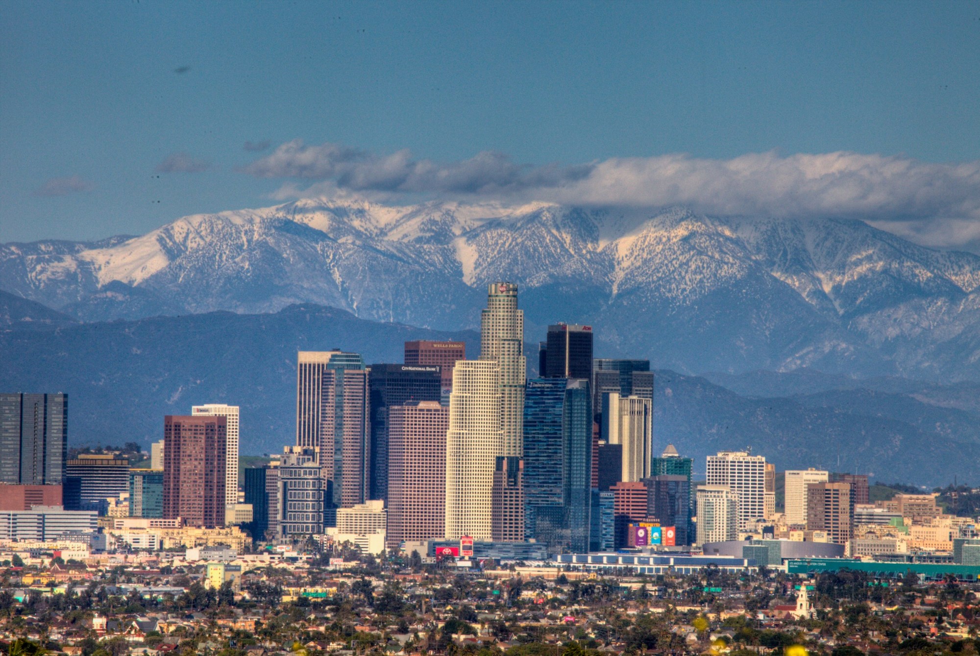 A view of the Downtown Los Angeles skyline with the snow-capped San Gabriel Mountains visible in the distance