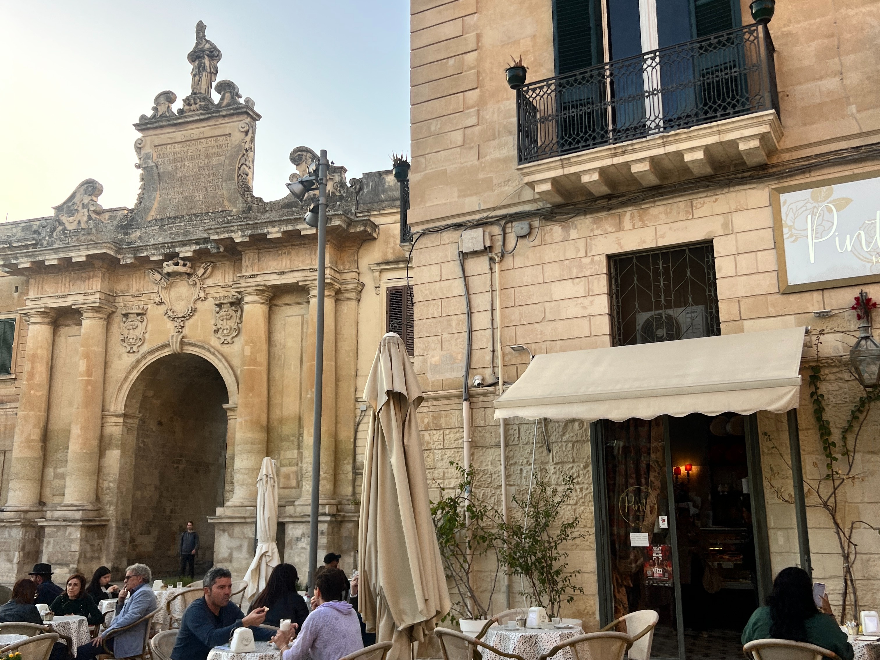 An outdoor eating area of a cafe next to an ancient building