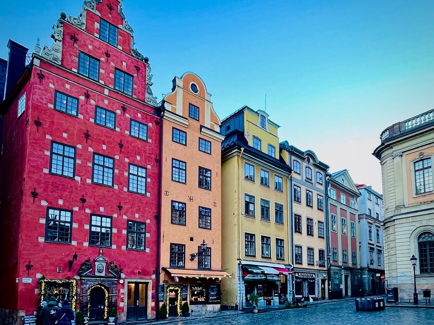 A picture of multicolored symmetrical buildings in a row during daytime.