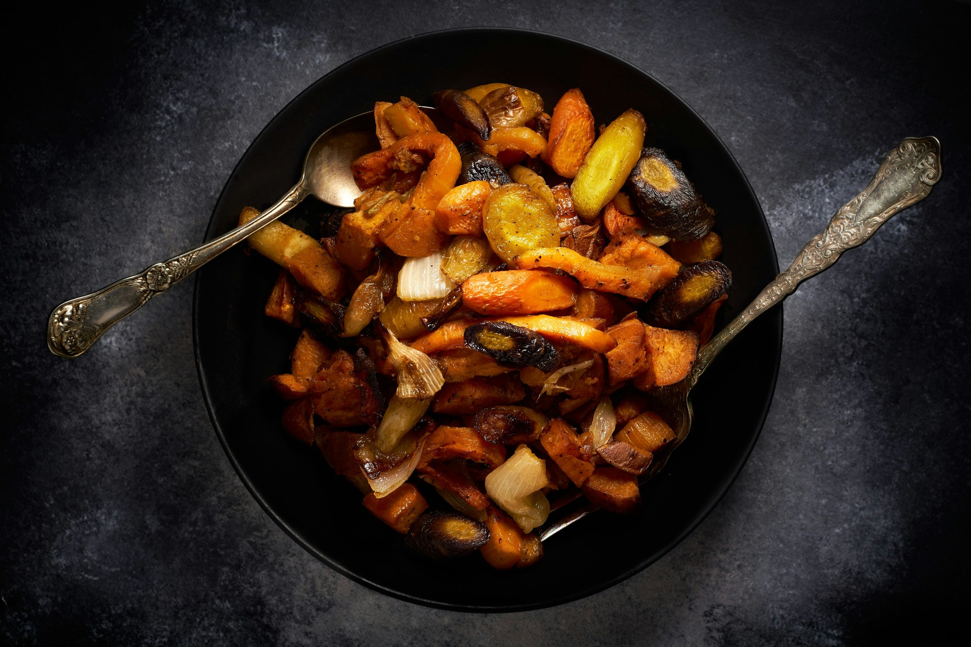 Cooked vegetables in a black bowl.