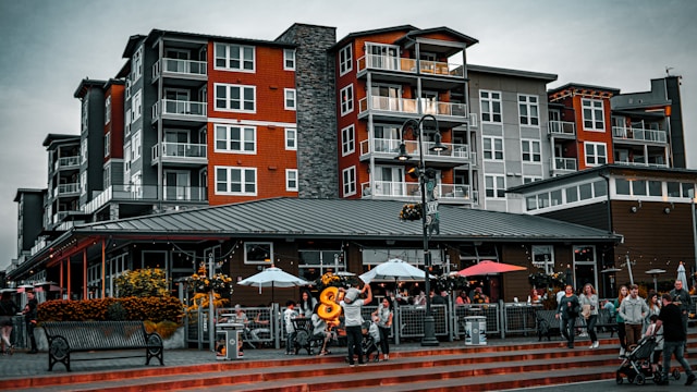 a red and gray apartment building with a lively restaurant inhabiting the bottom floor of the building