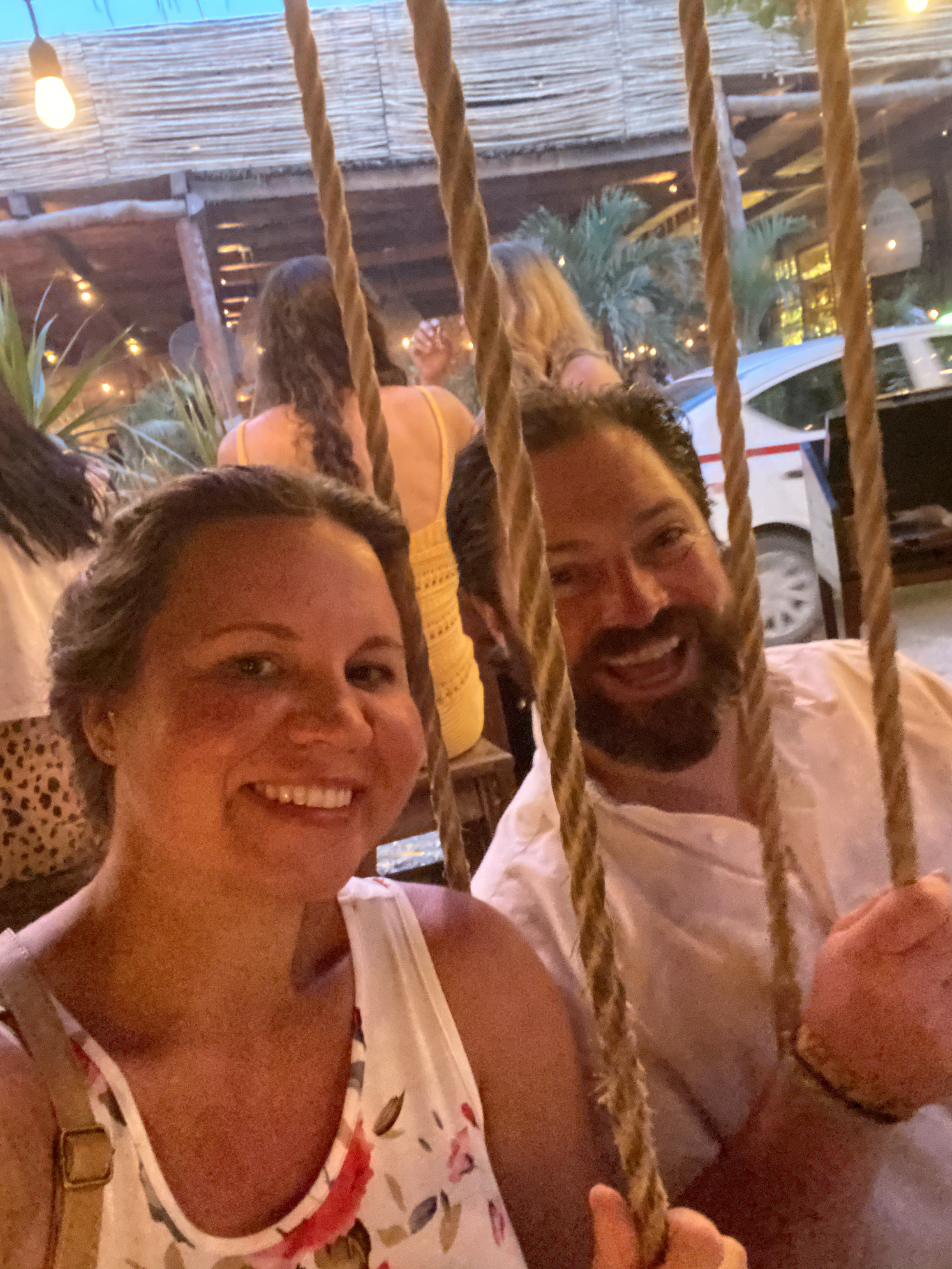 Travel advisor Tiffany sitting on rope swings with partner by a busy street