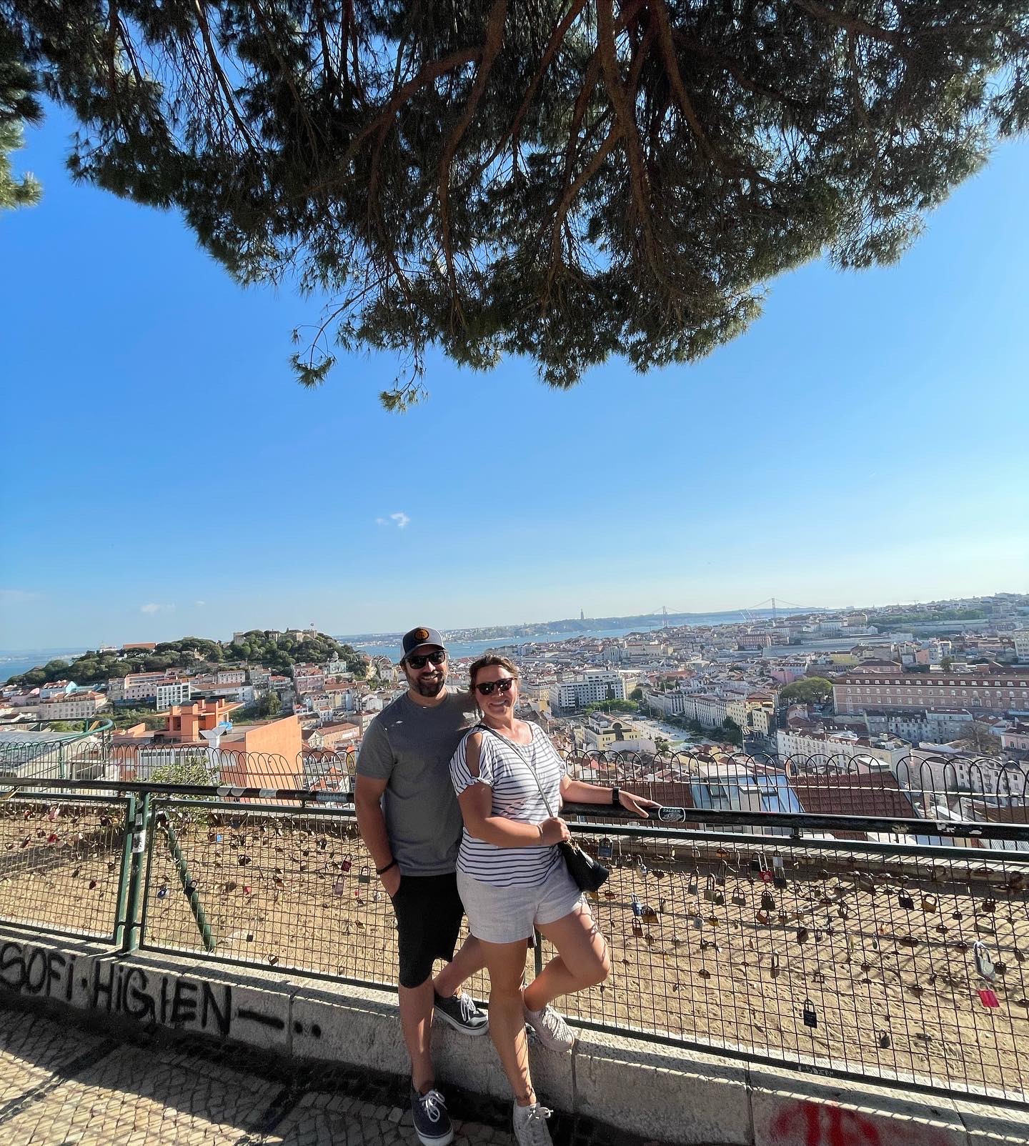 Travel advisor Tiffany and male companion standing by a wire railing overlooking a city