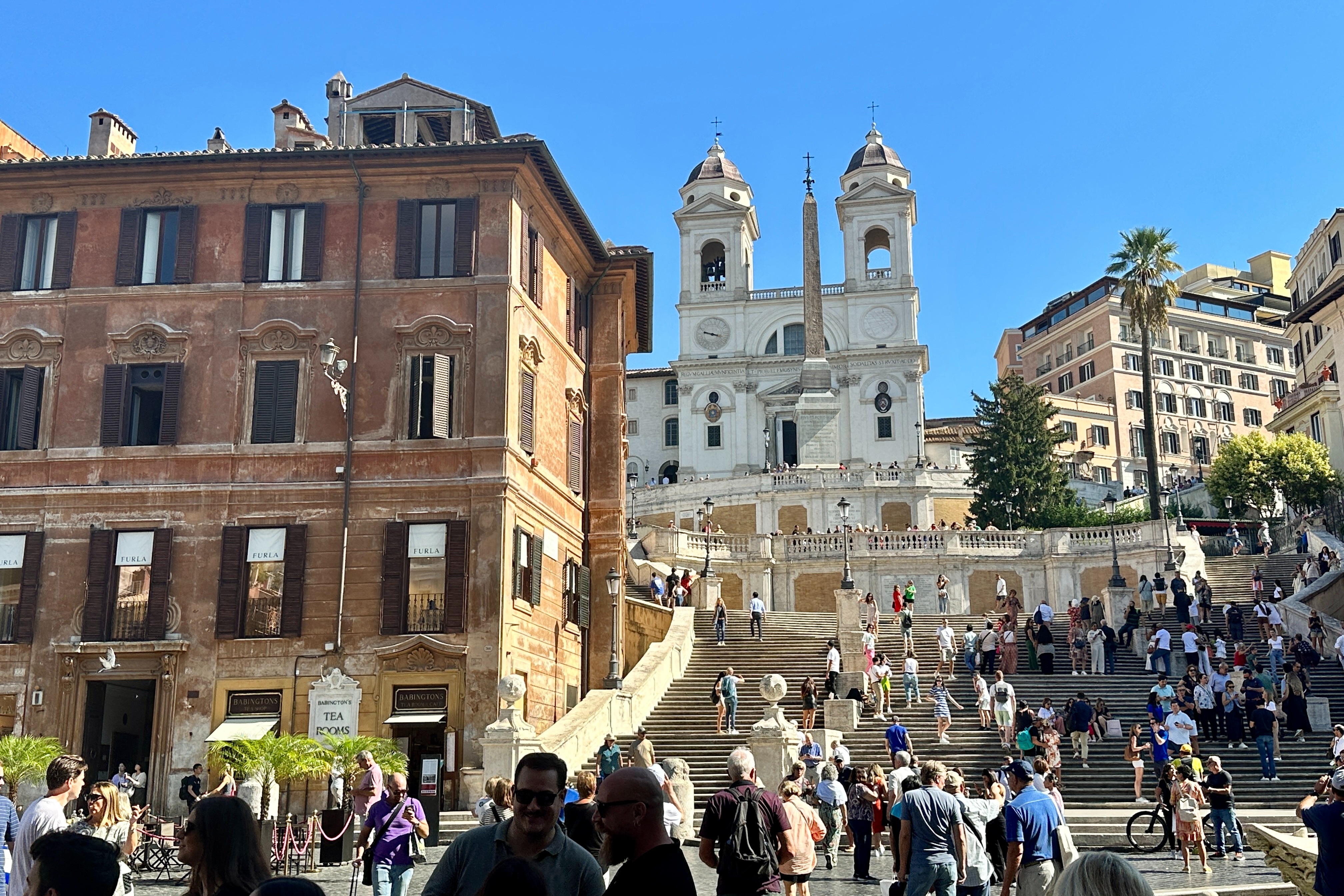 A picture taken of Spanish steps surrounded by tall buildings.
