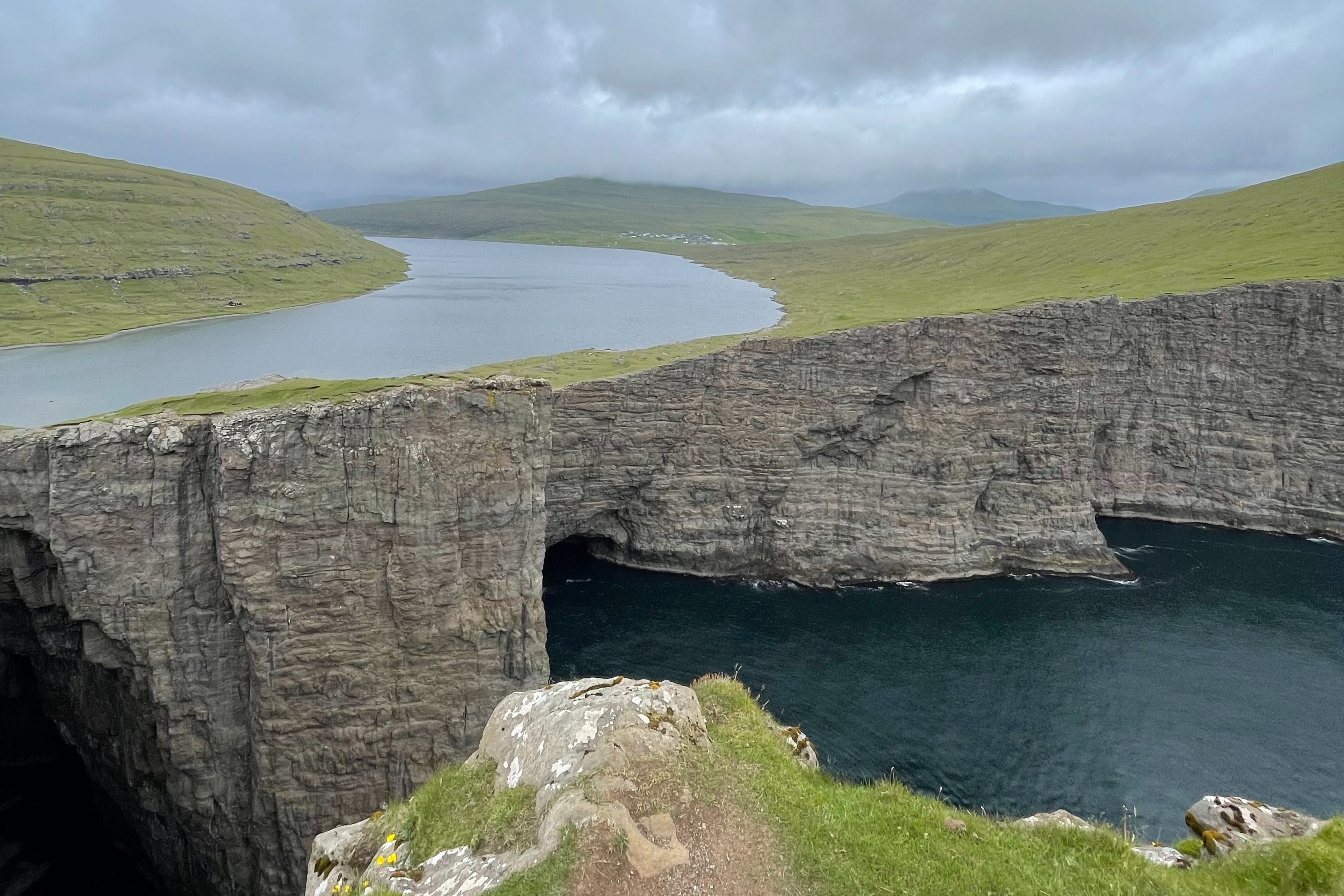A view of the rocky cliffs, grassy hills and river in Sørvágsvatn which is also known as The Lake above the Ocean.