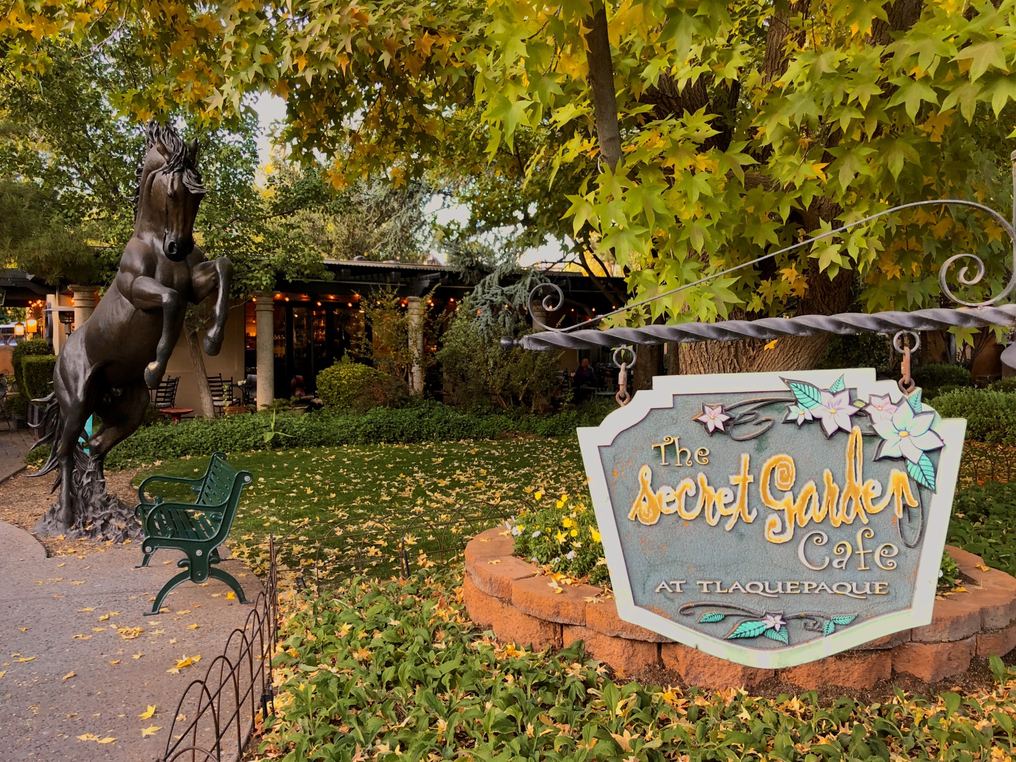 A garden in the daytime with a sign reading "The Secret Garden Cafe"