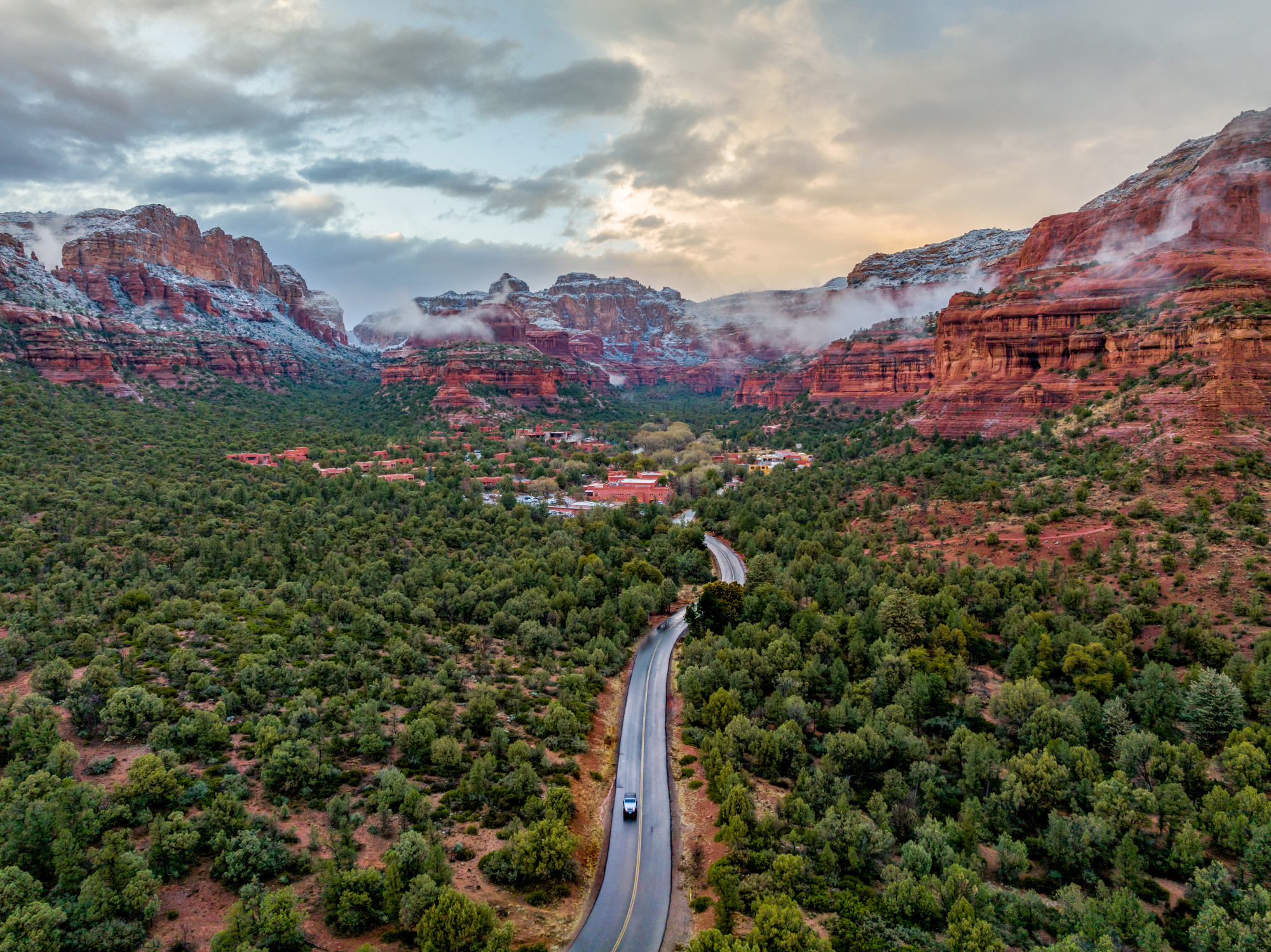 Aerial view of a road between forests with mountains in the distance