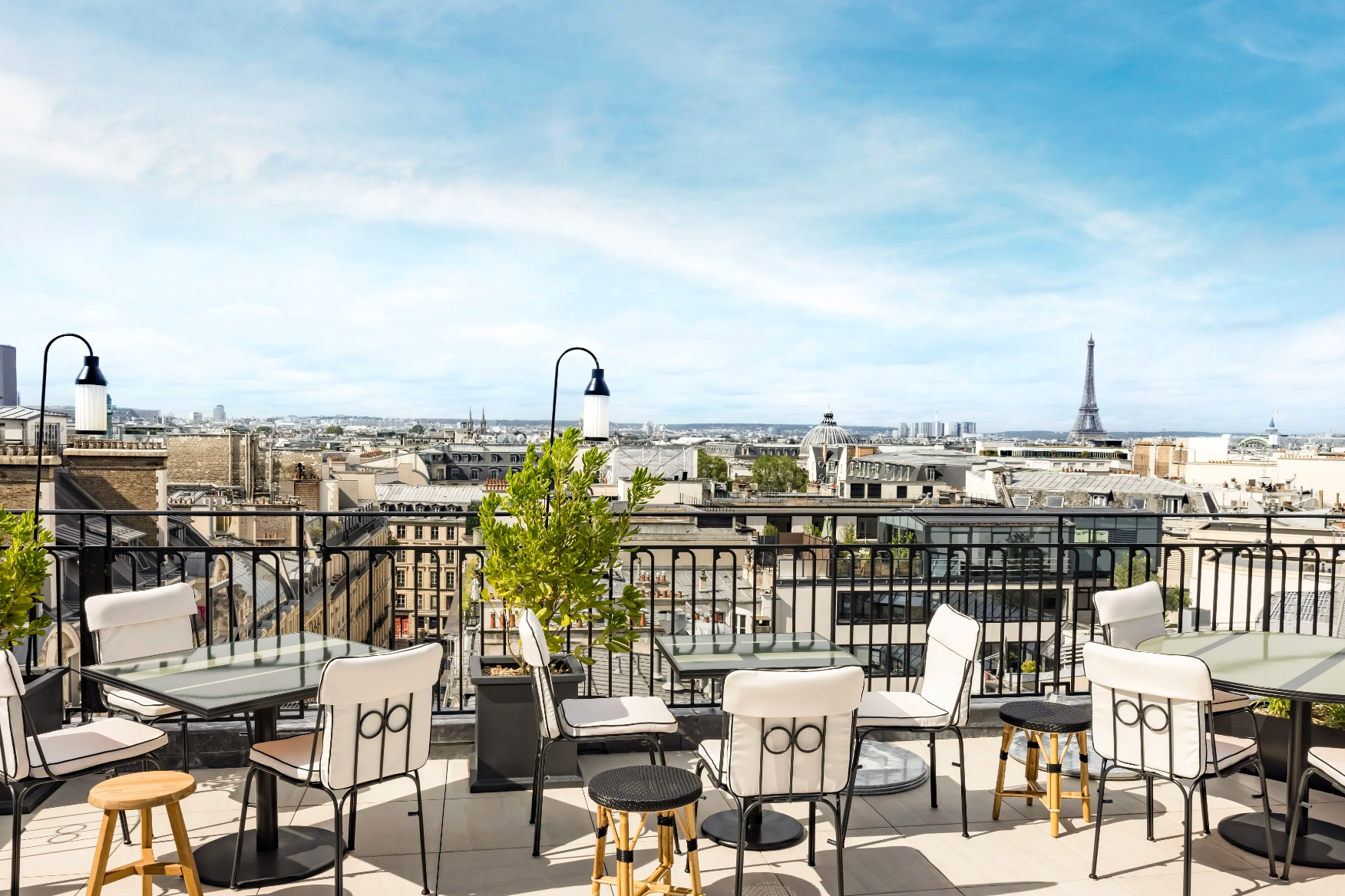 tables and chairs on a sunny terrace overlooking a city