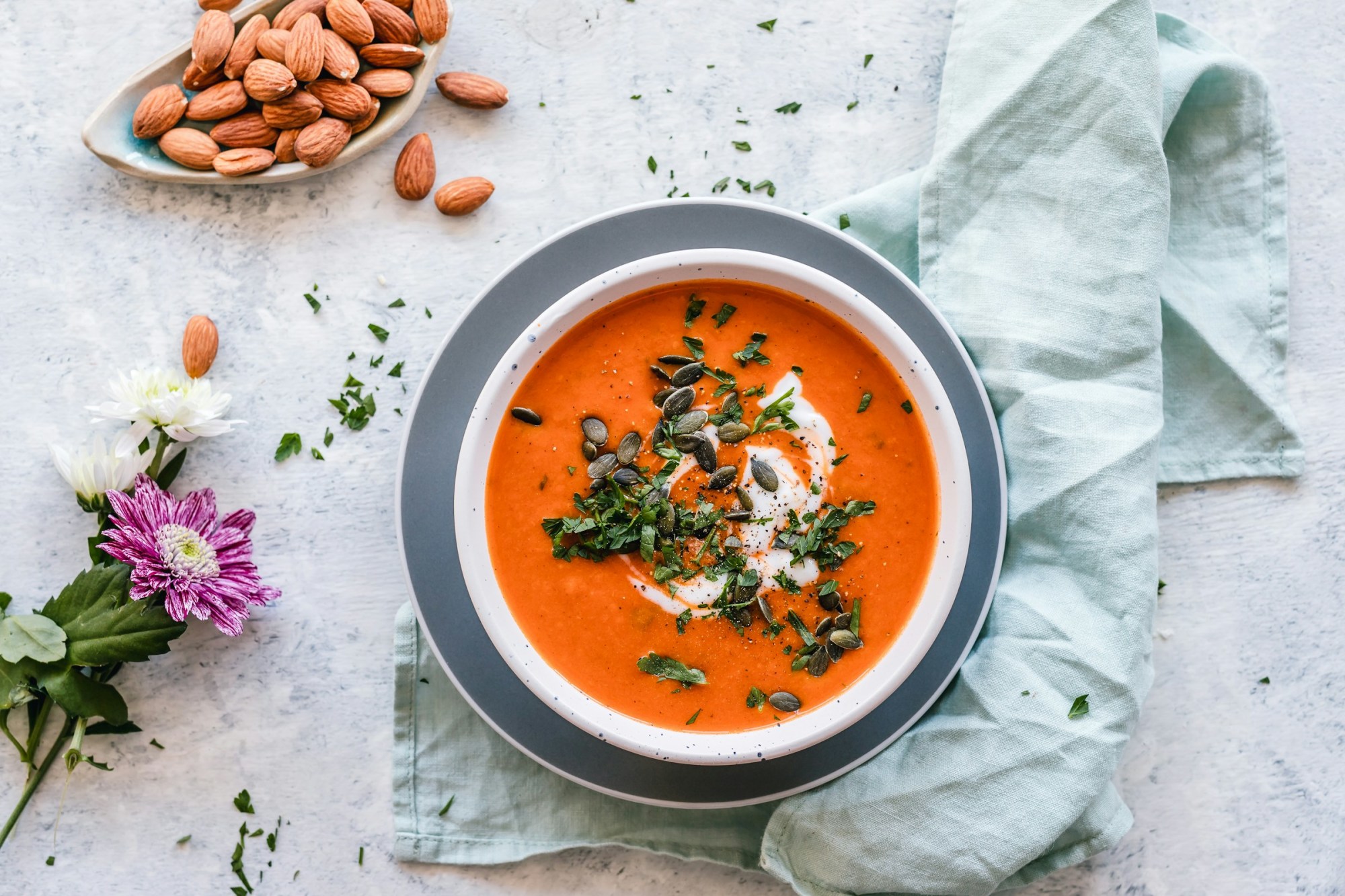 Harira sits in a contemporary bowl with a cream, nut and herb garnish and almonds off to the side