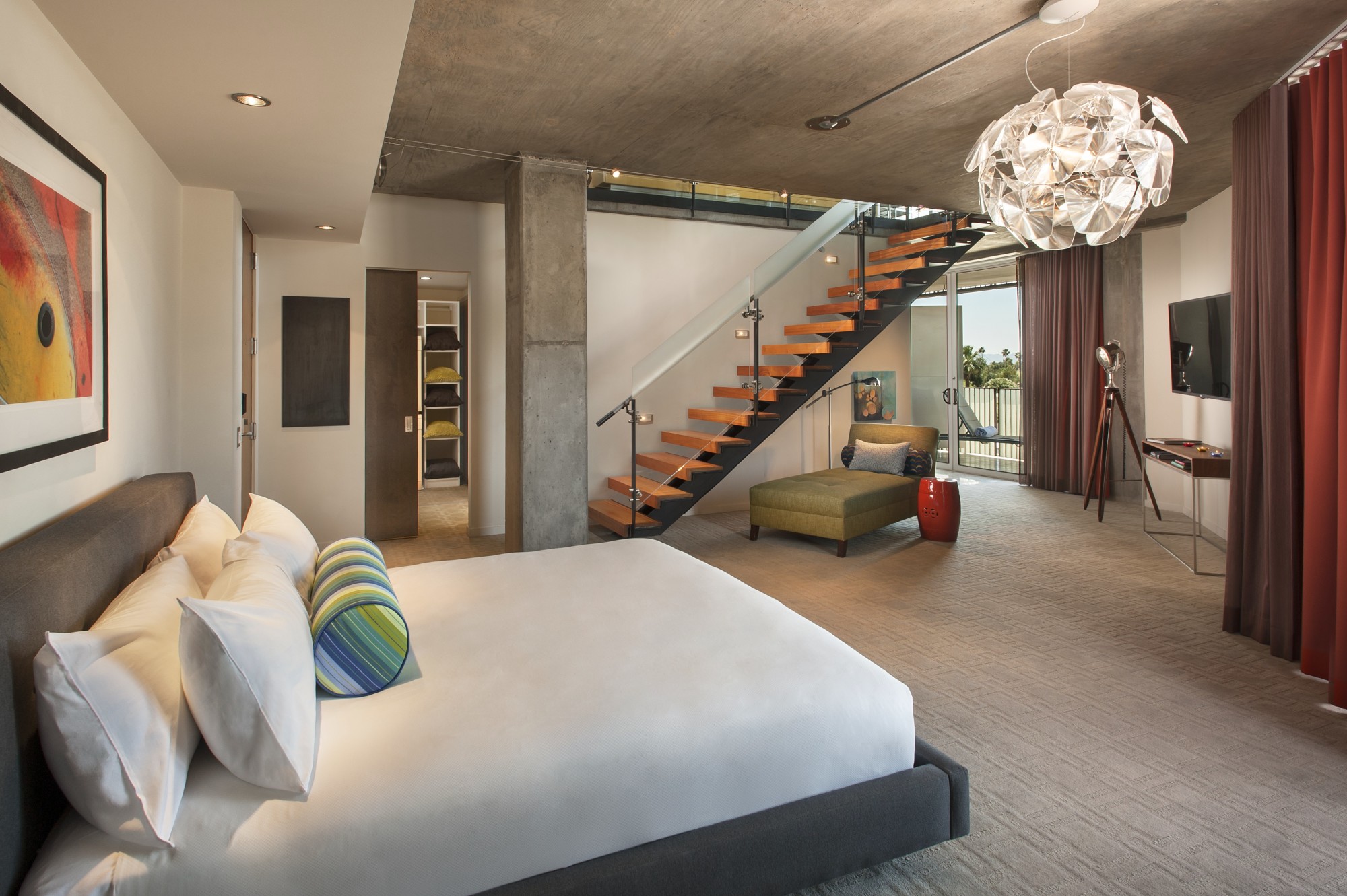 a white bed in an apartment with a floating wooden staircase
