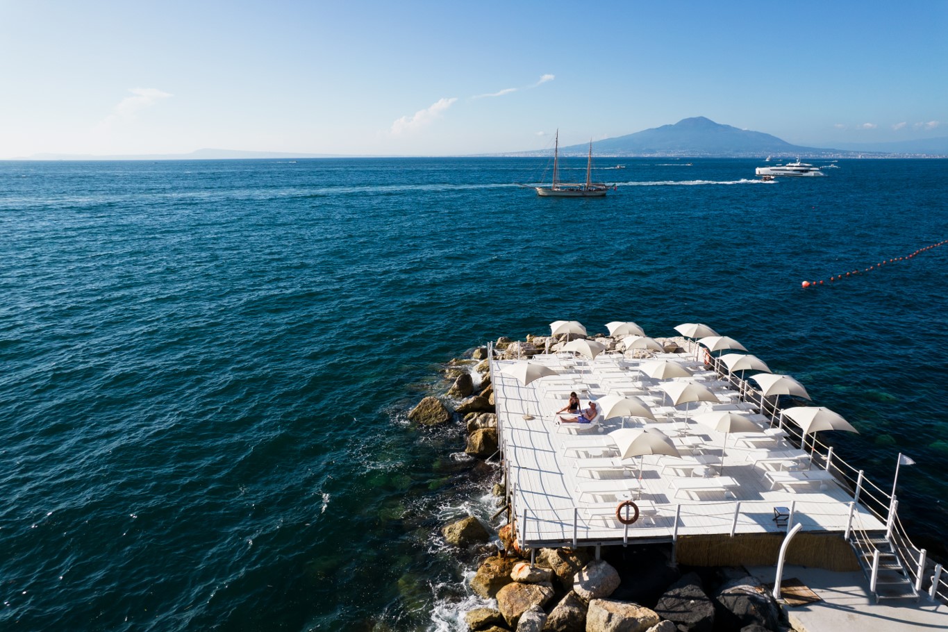 a pier dotted with white lounge chairs and umbrellas