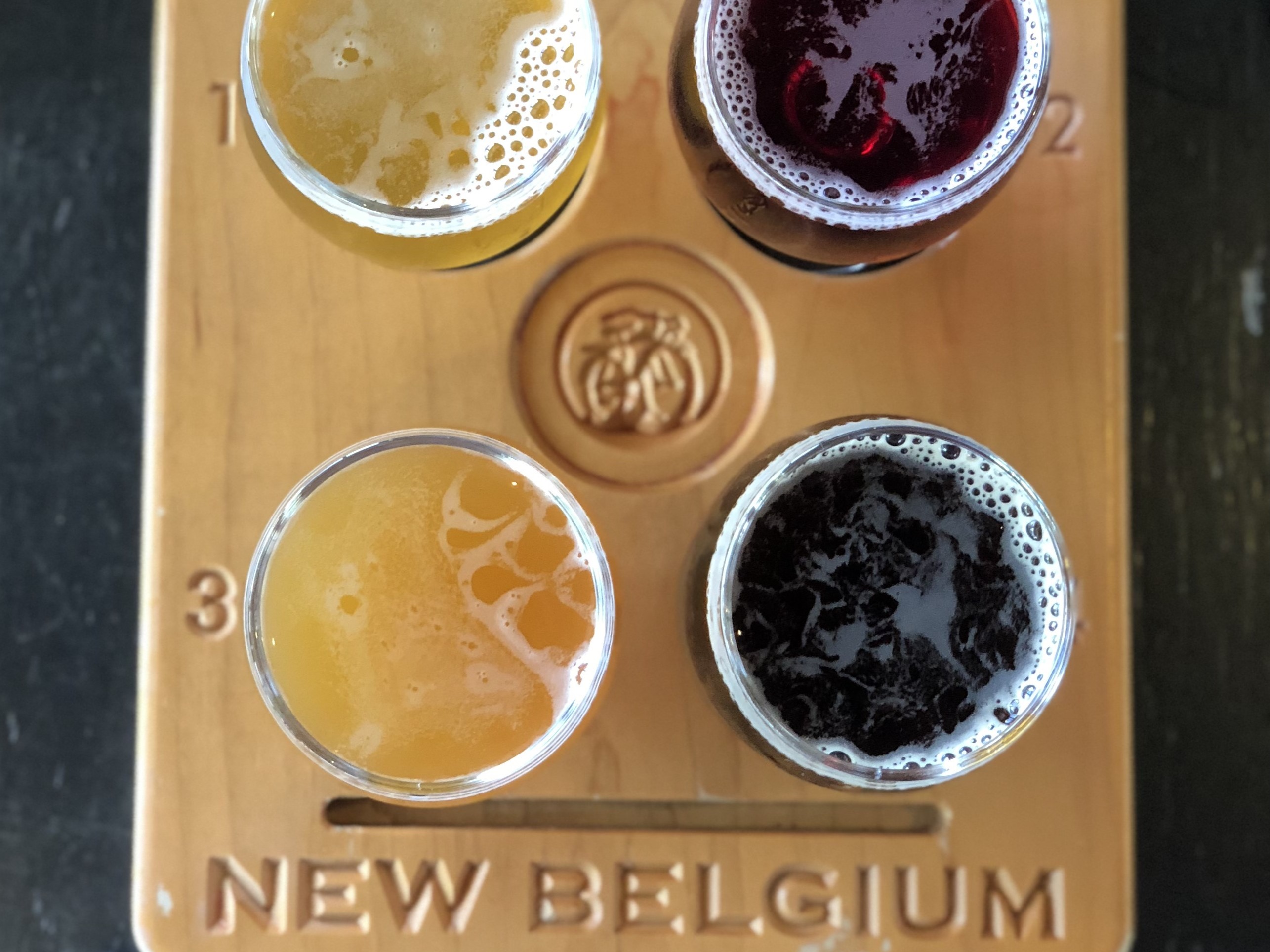 Four beers on a wooden New Belgium flight board taken from above.