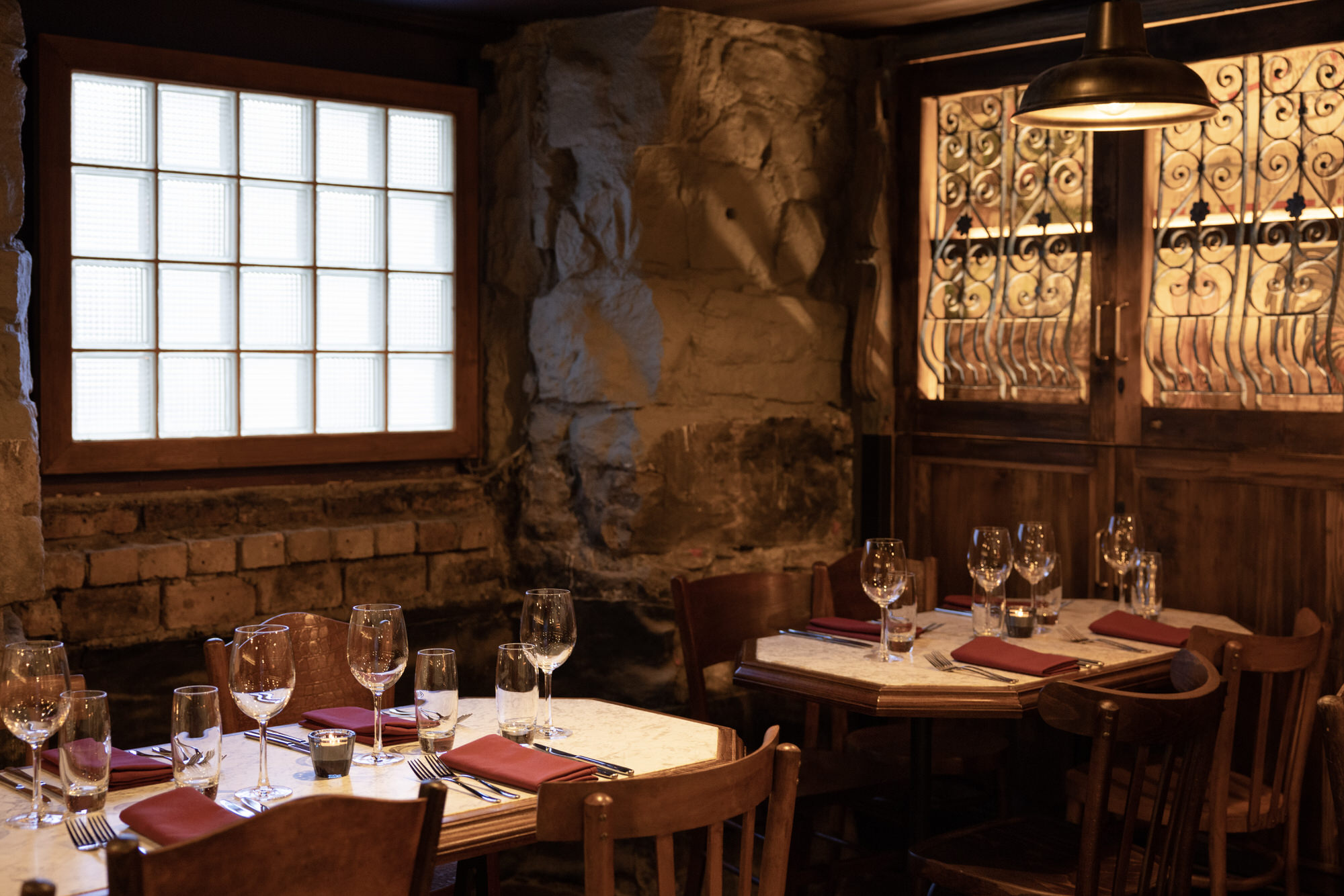 The interior of Stravaigin, with wooden tables set with red napkins and brick walls.