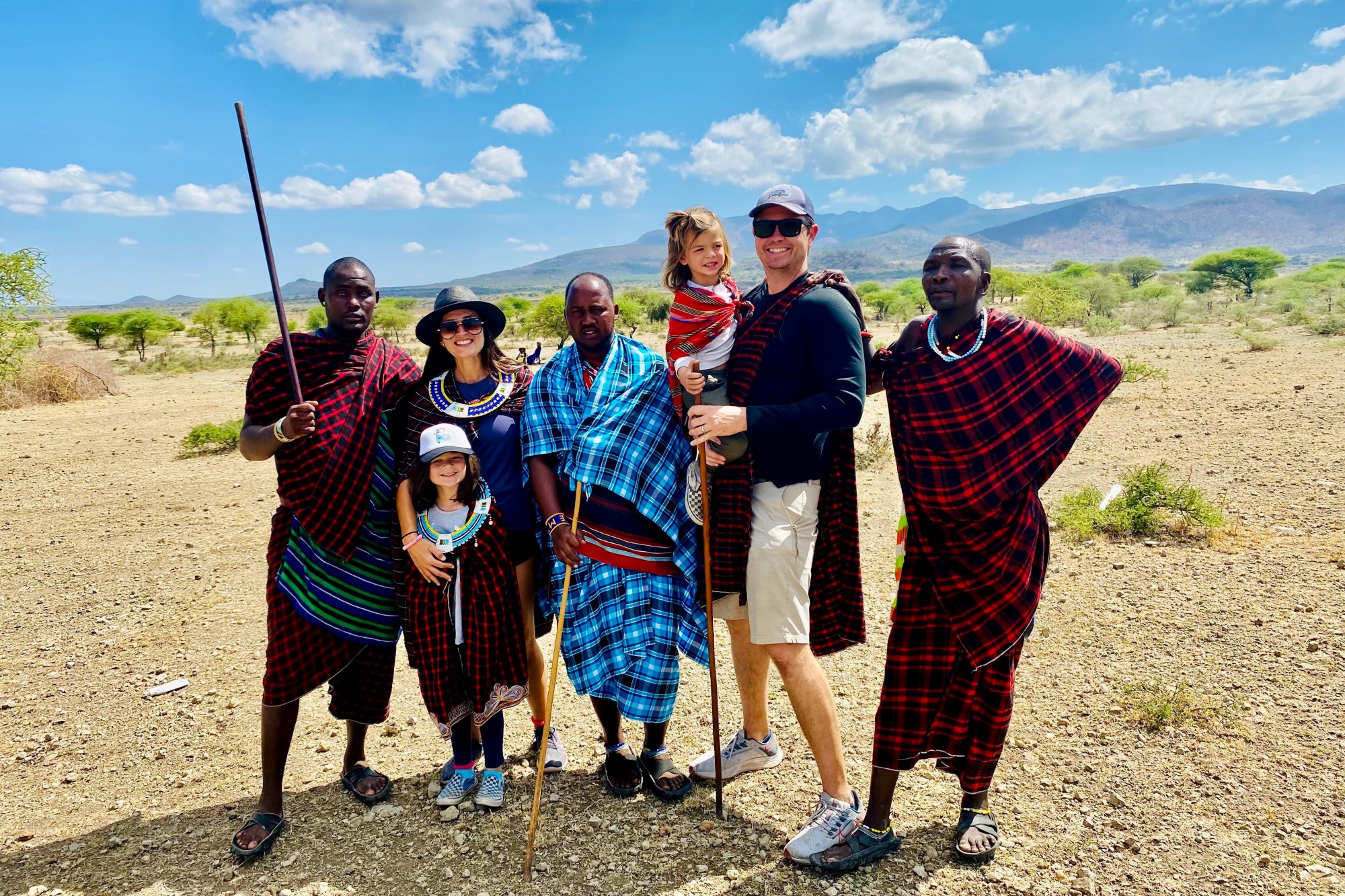 three men, a woman, and two small children stand in a desert