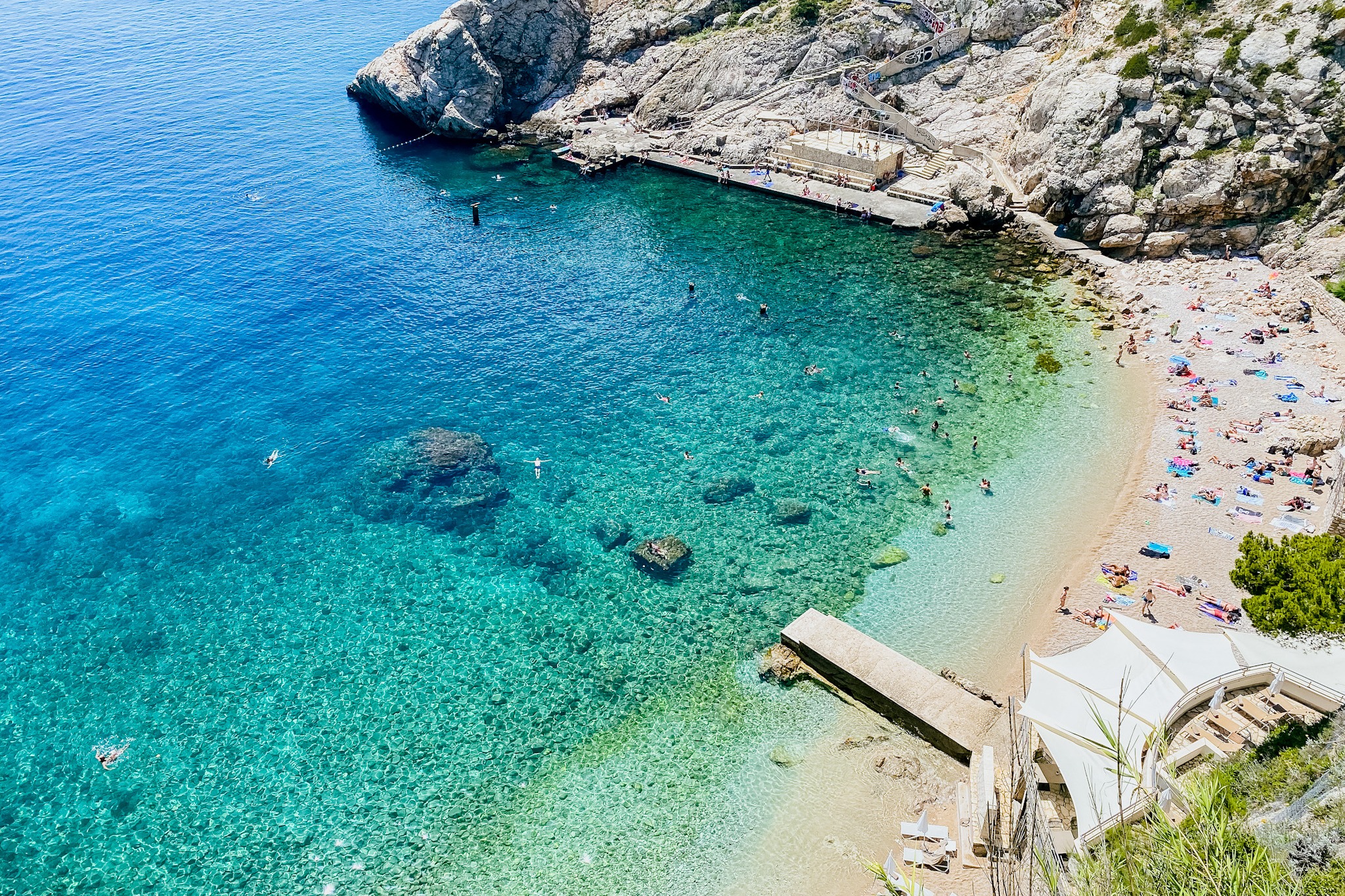 The seashore with tourists on the beach as seen from a hotel room above.