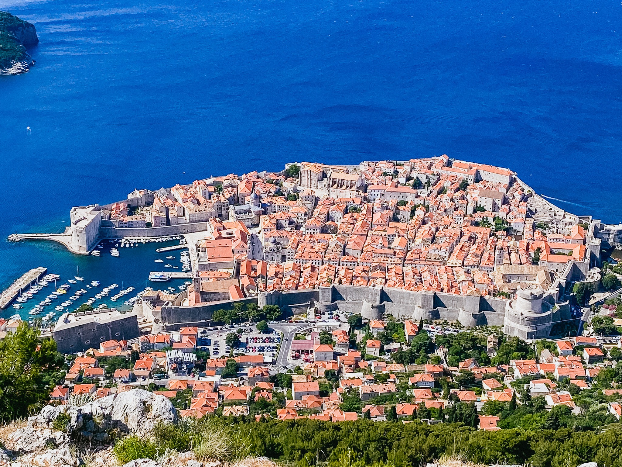 A picture of the city with red-roofed buildings and the deep blue sea from a cable car.